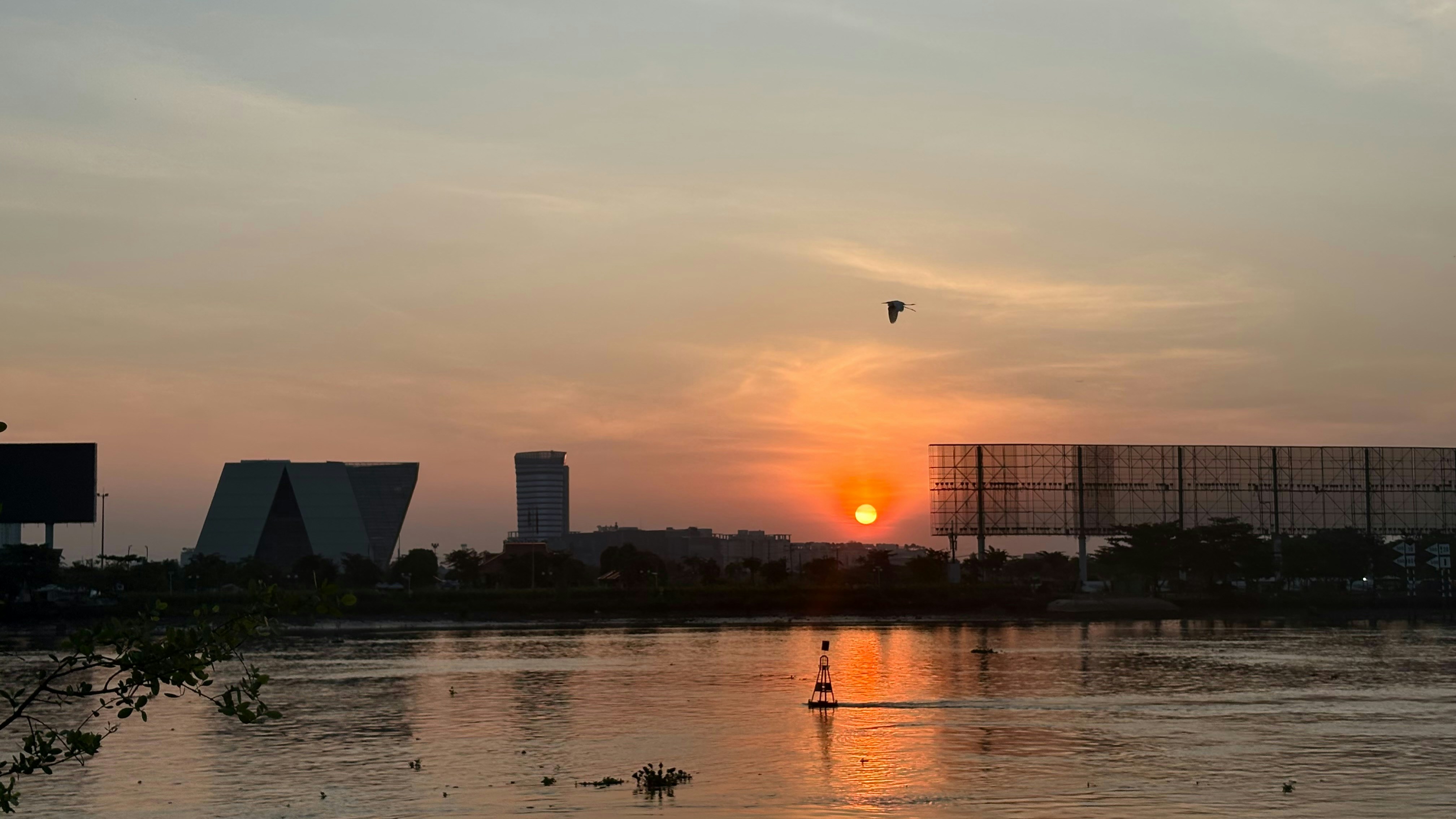 Sunset over a calm body of water with buildings.