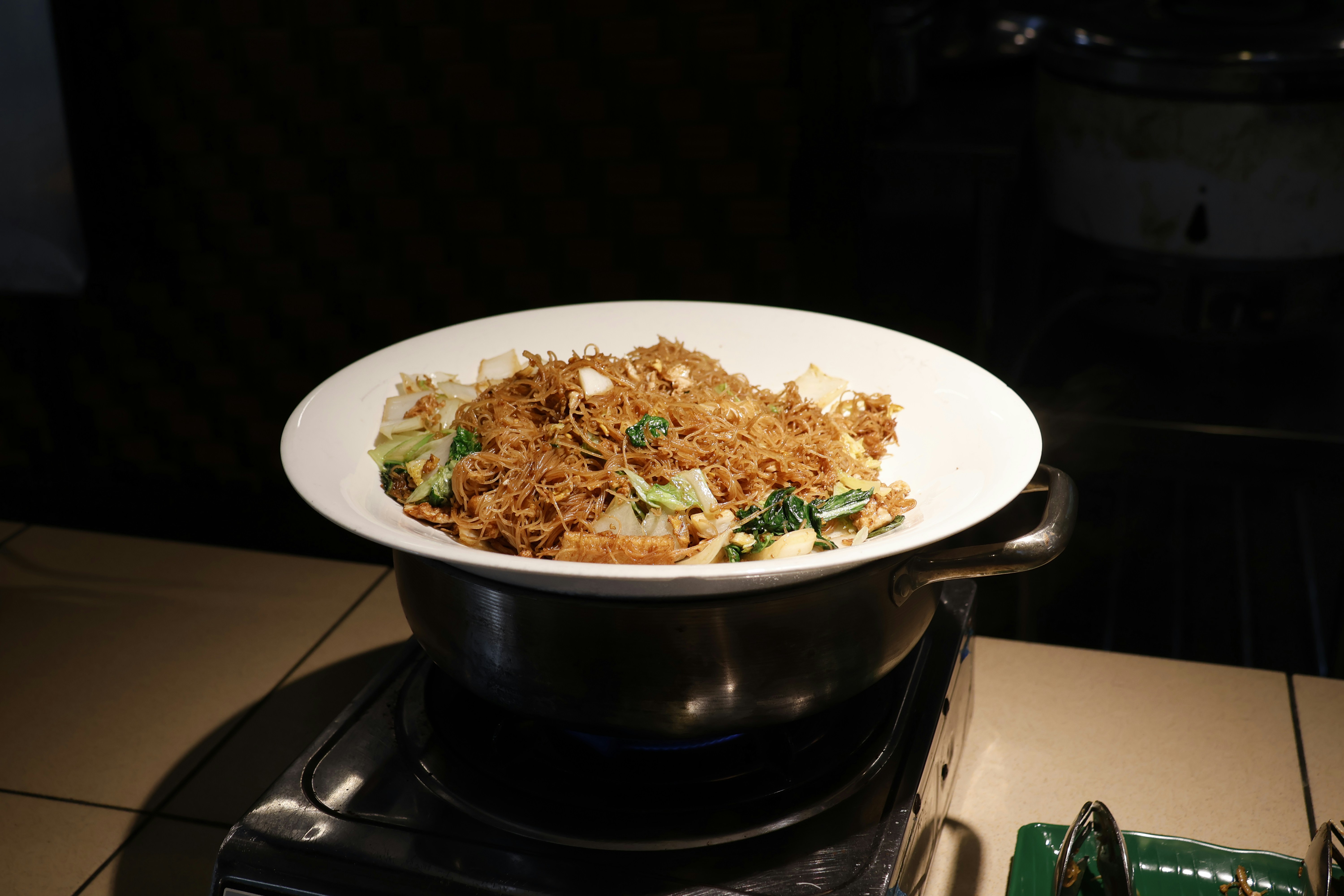 A plate of noodles with vegetables on a stove.