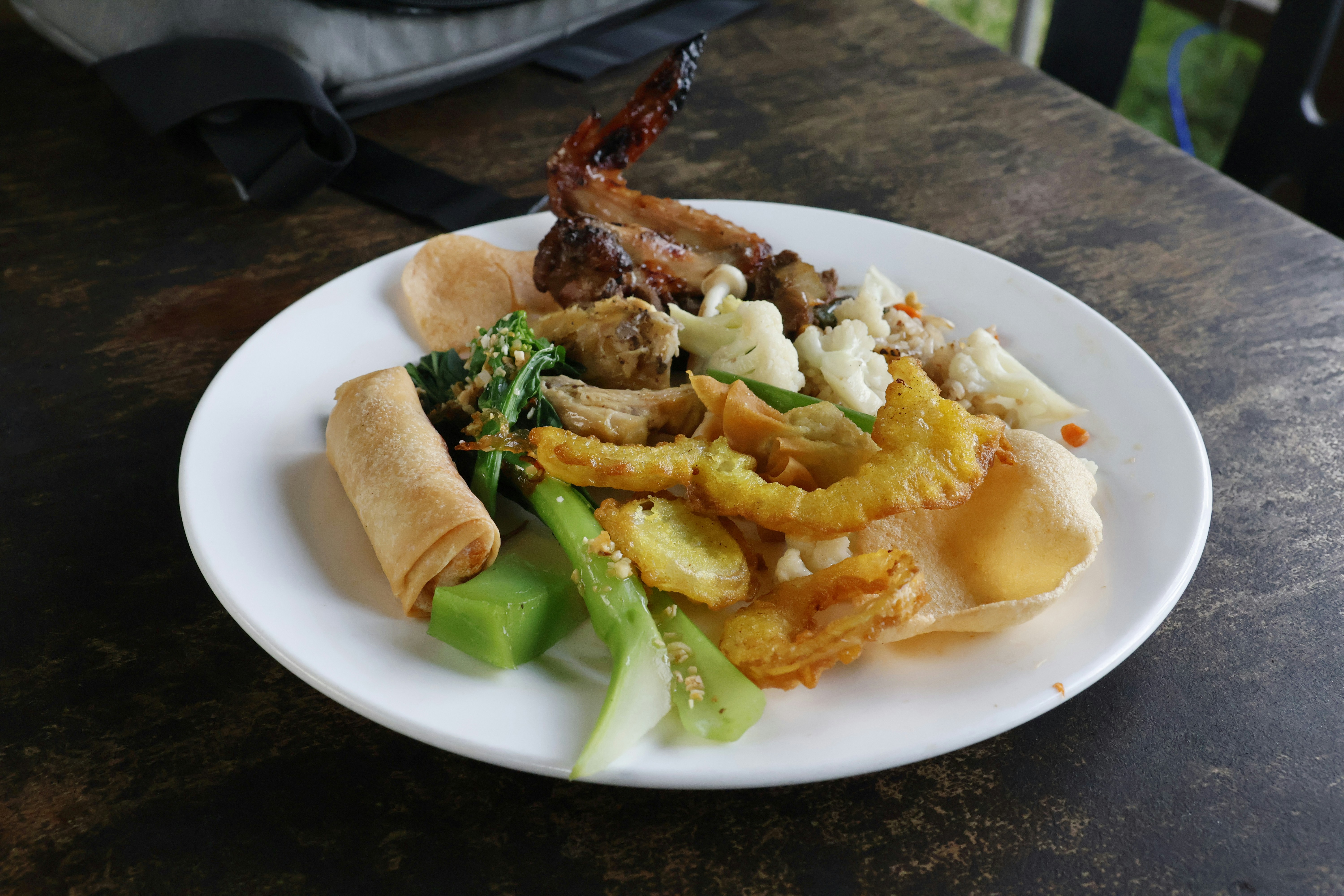 A plate of assorted food including spring rolls and vegetables