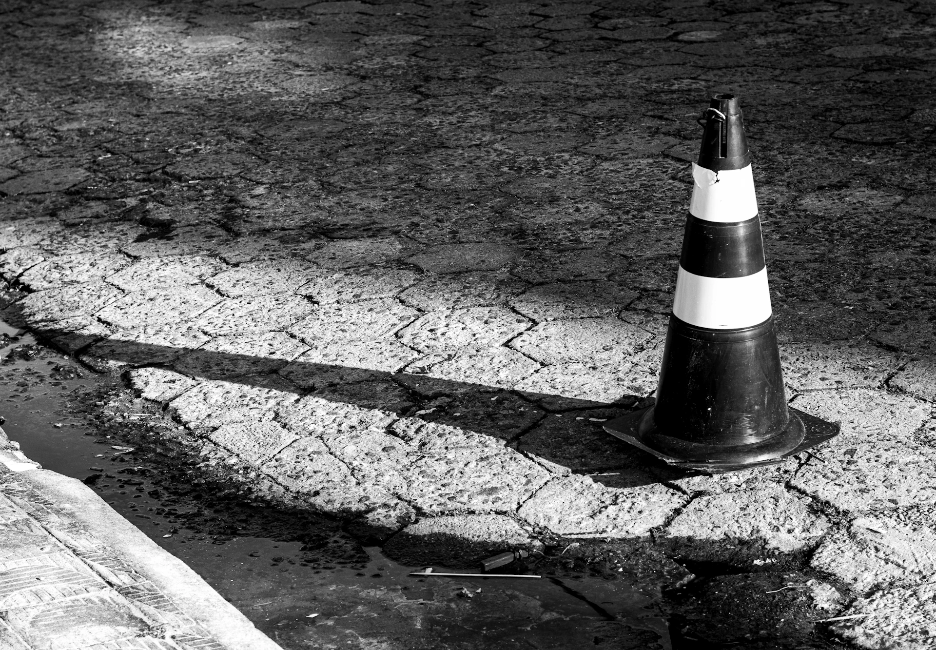 A traffic cone casts a long shadow on pavement.