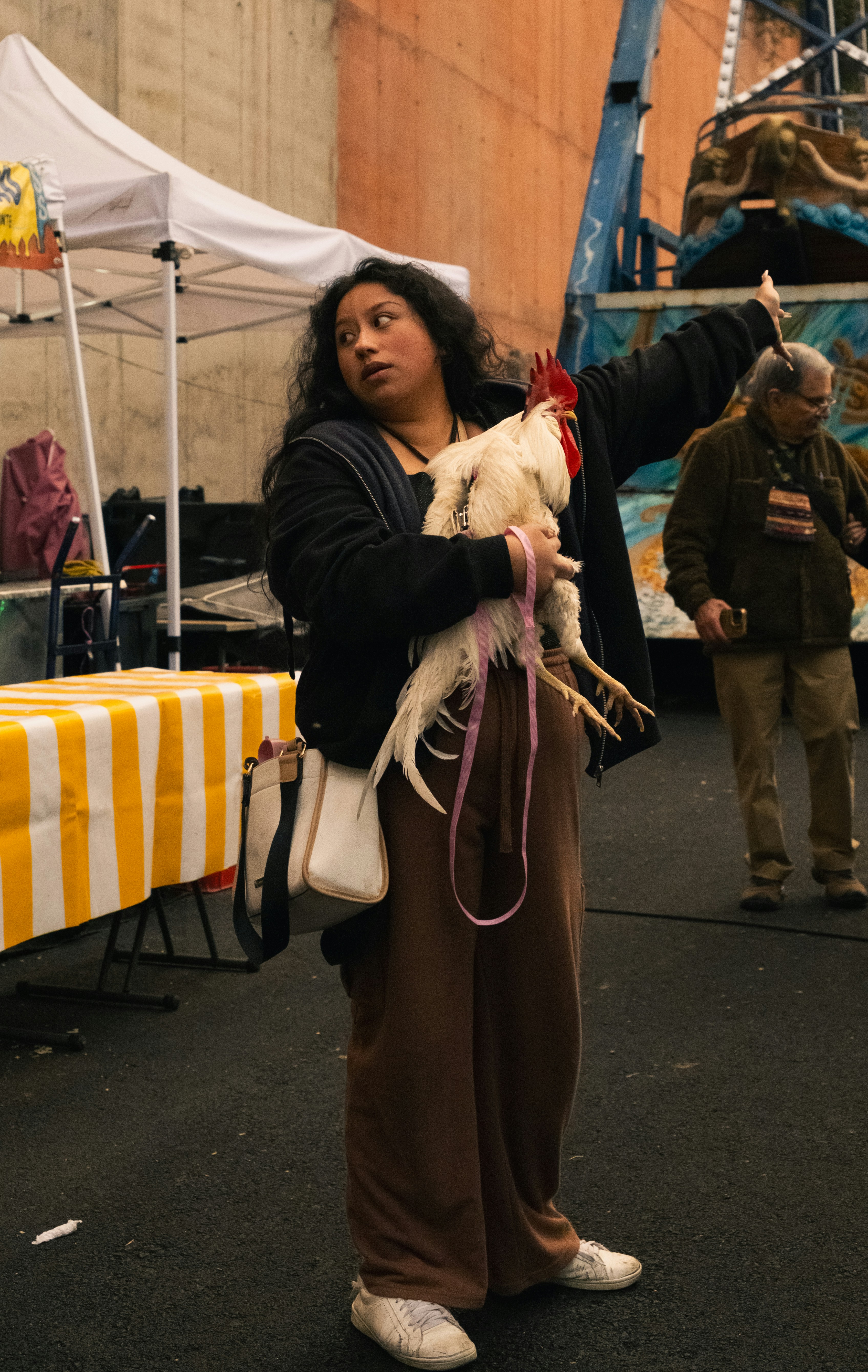 Femme tenant un coq blanc dans un marché en plein air.