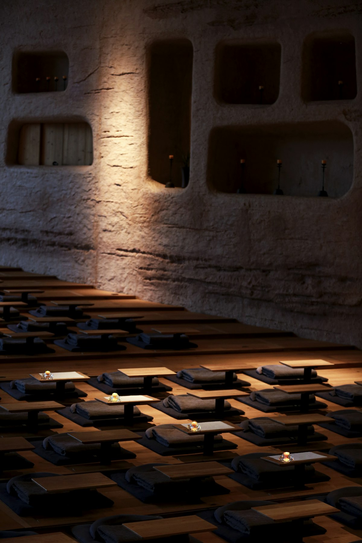 Rows of mats and low tables in a dimly lit communal hall, retreat-center stillness