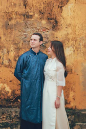 Couple in traditional vietnamese áo dài against textured wall