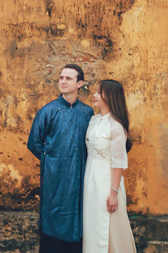 Couple in traditional vietnamese áo dài against textured wall