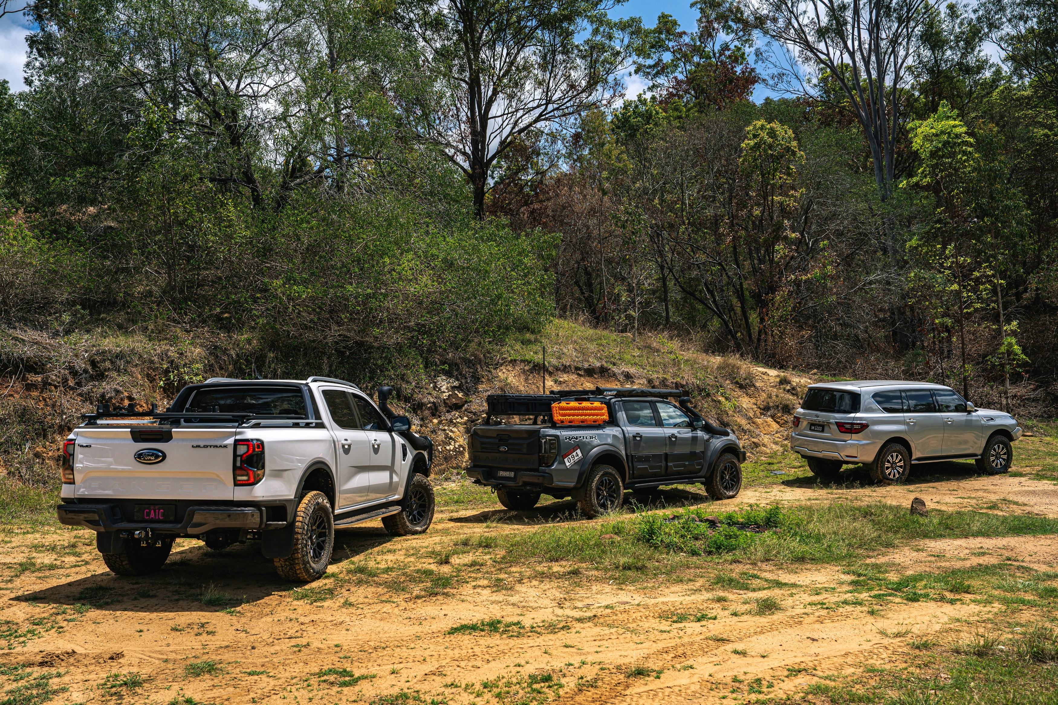 Three off-road vehicles parked on a dirt track.