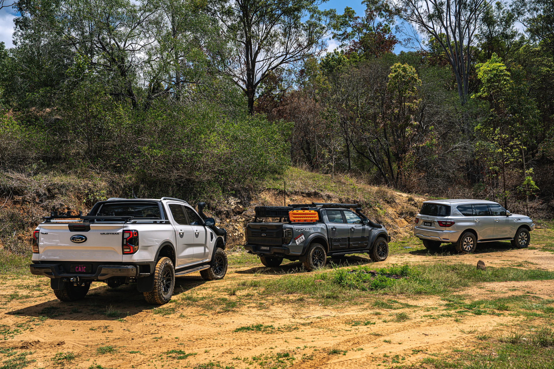Three off-road vehicles parked on a dirt track