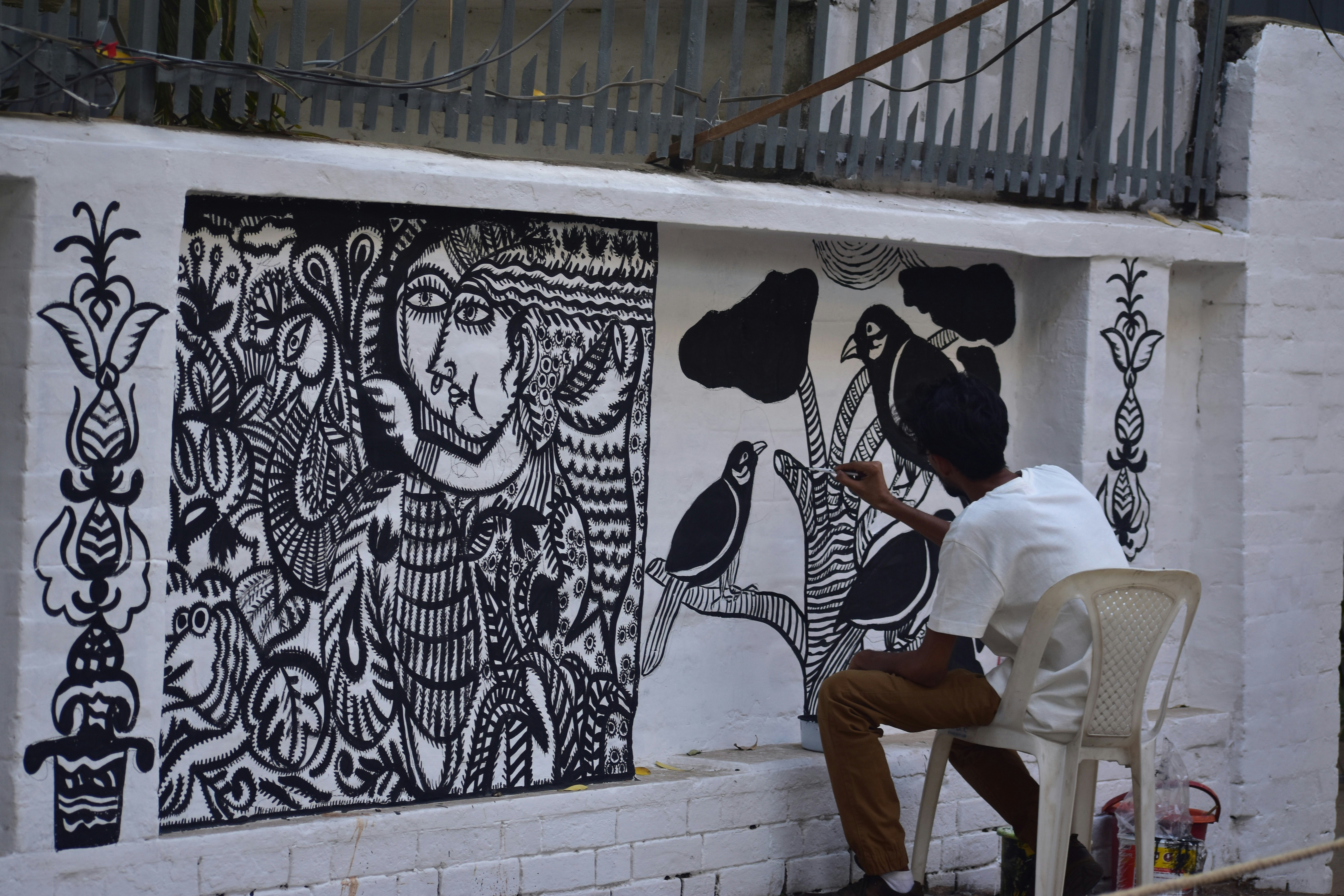 Artist painting a mural on a white wall