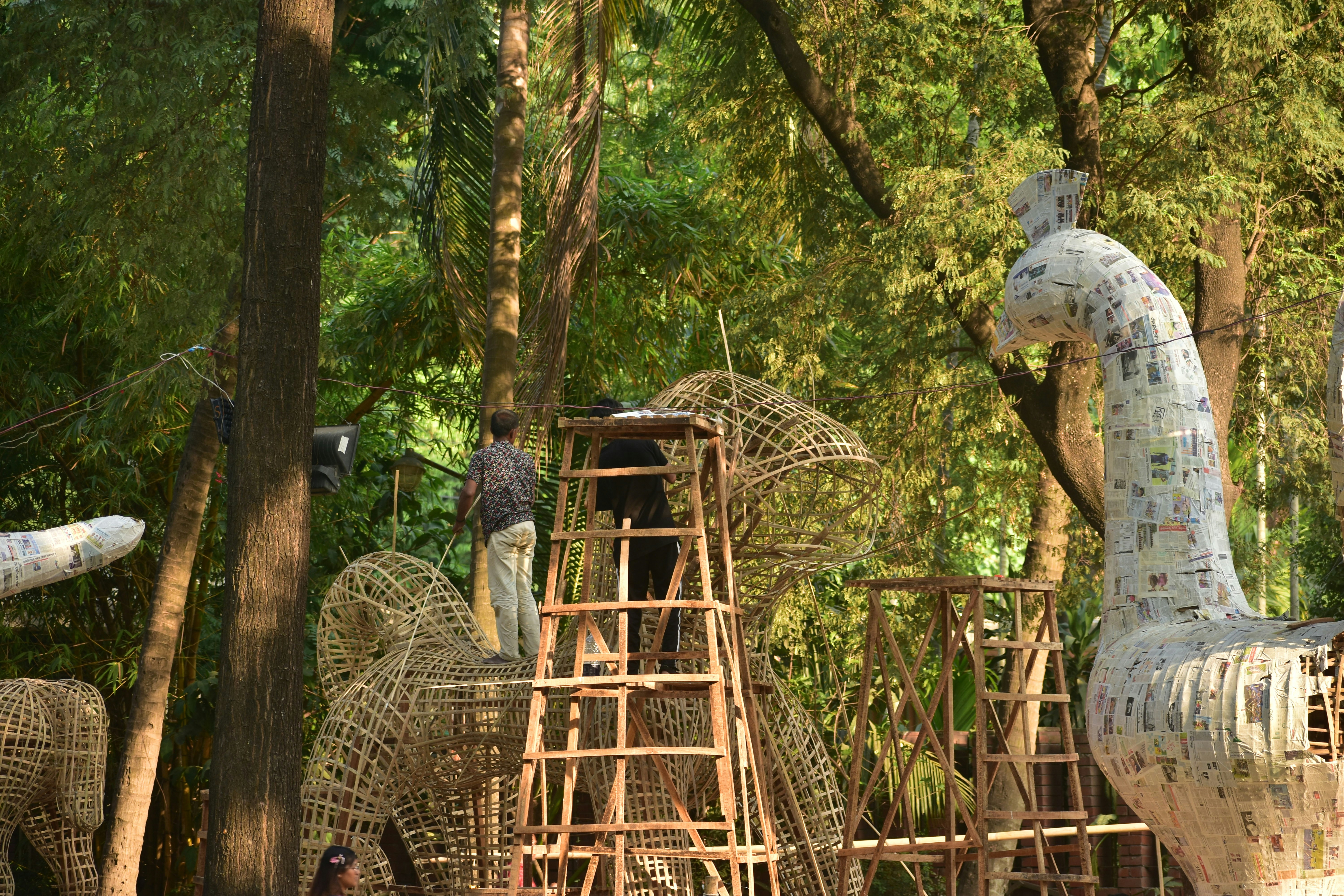 Artist working on large sculptures in a forest.