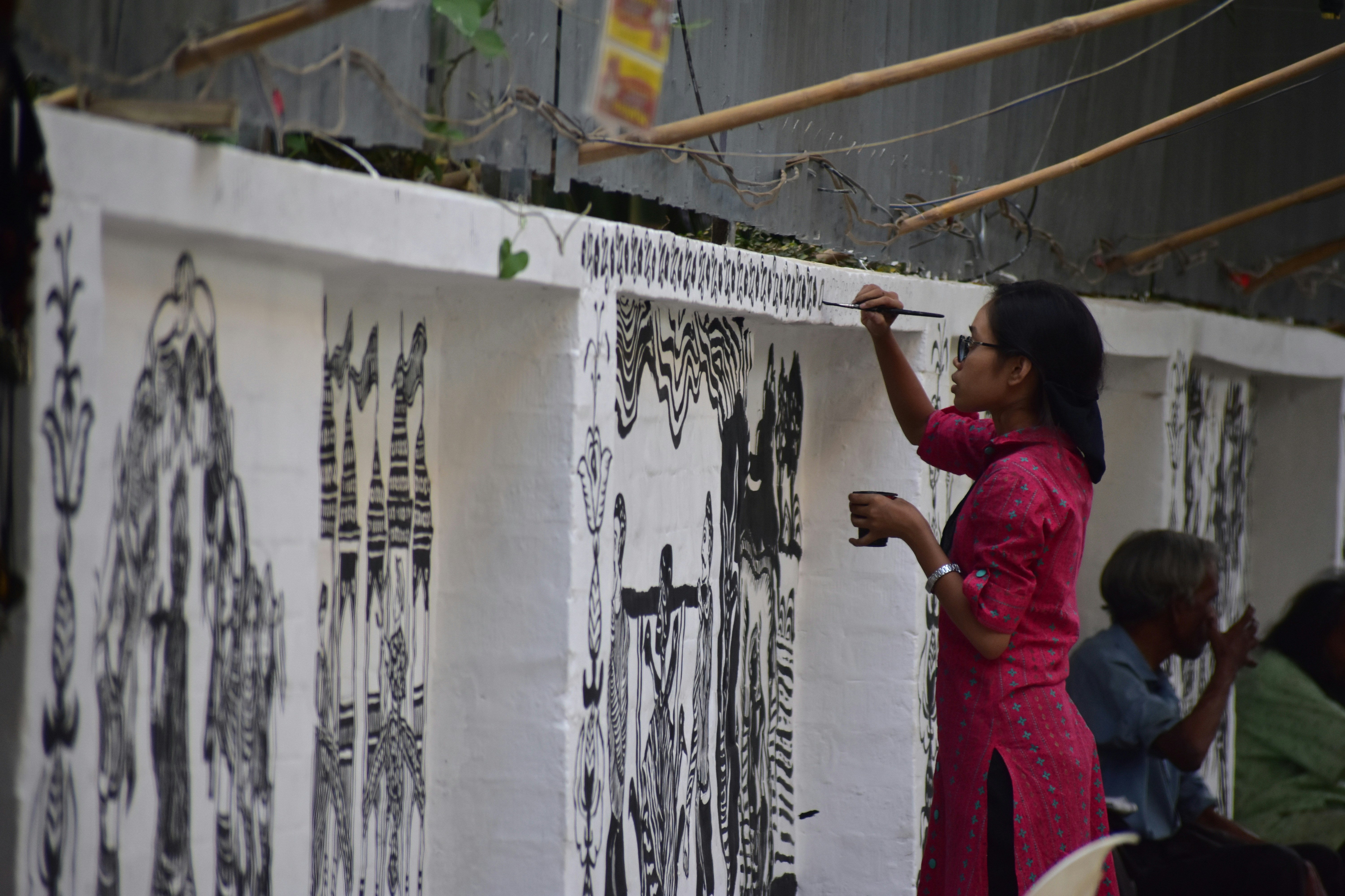 Woman painting a mural with black ink