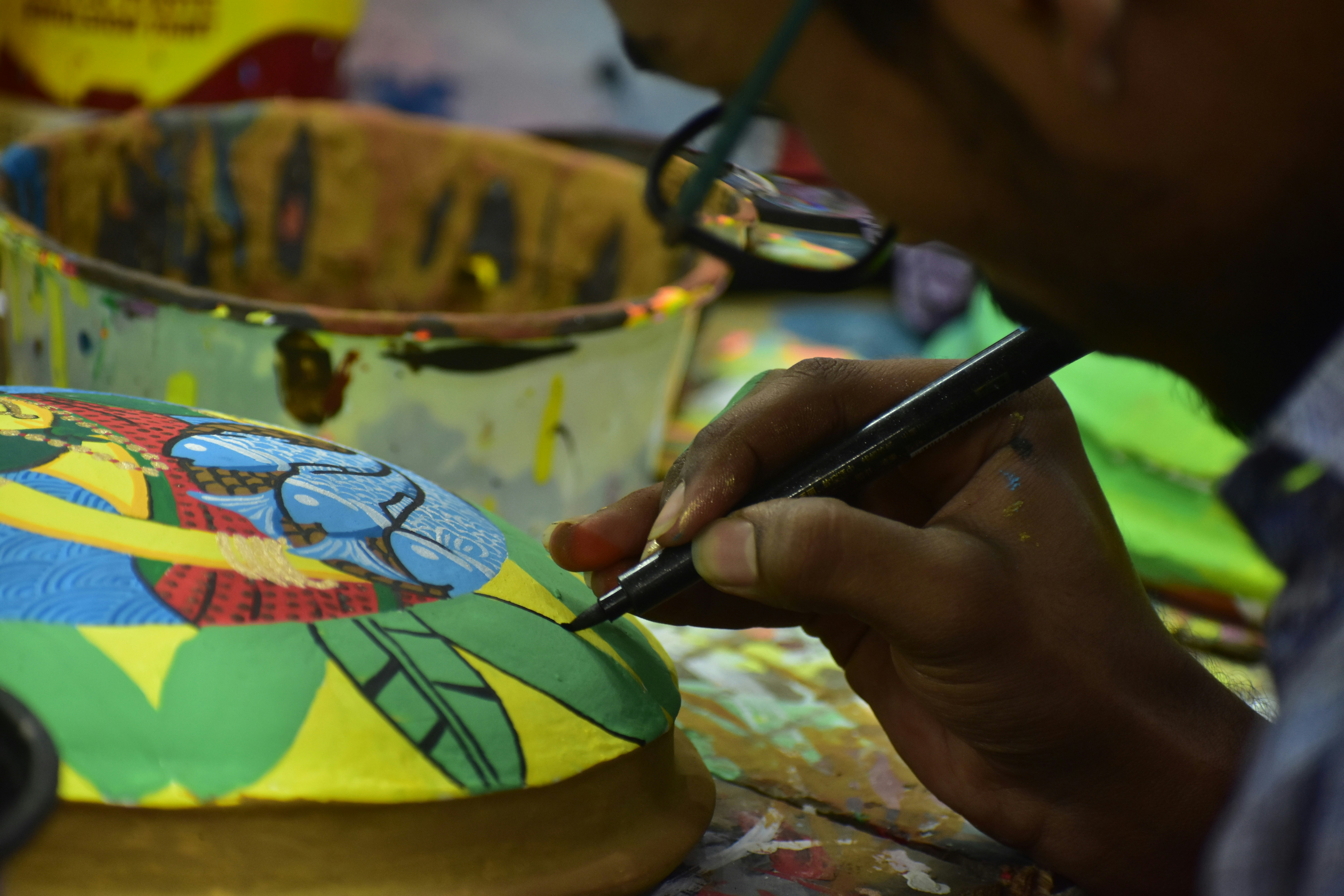 Artist painting intricate details on a colorful object.