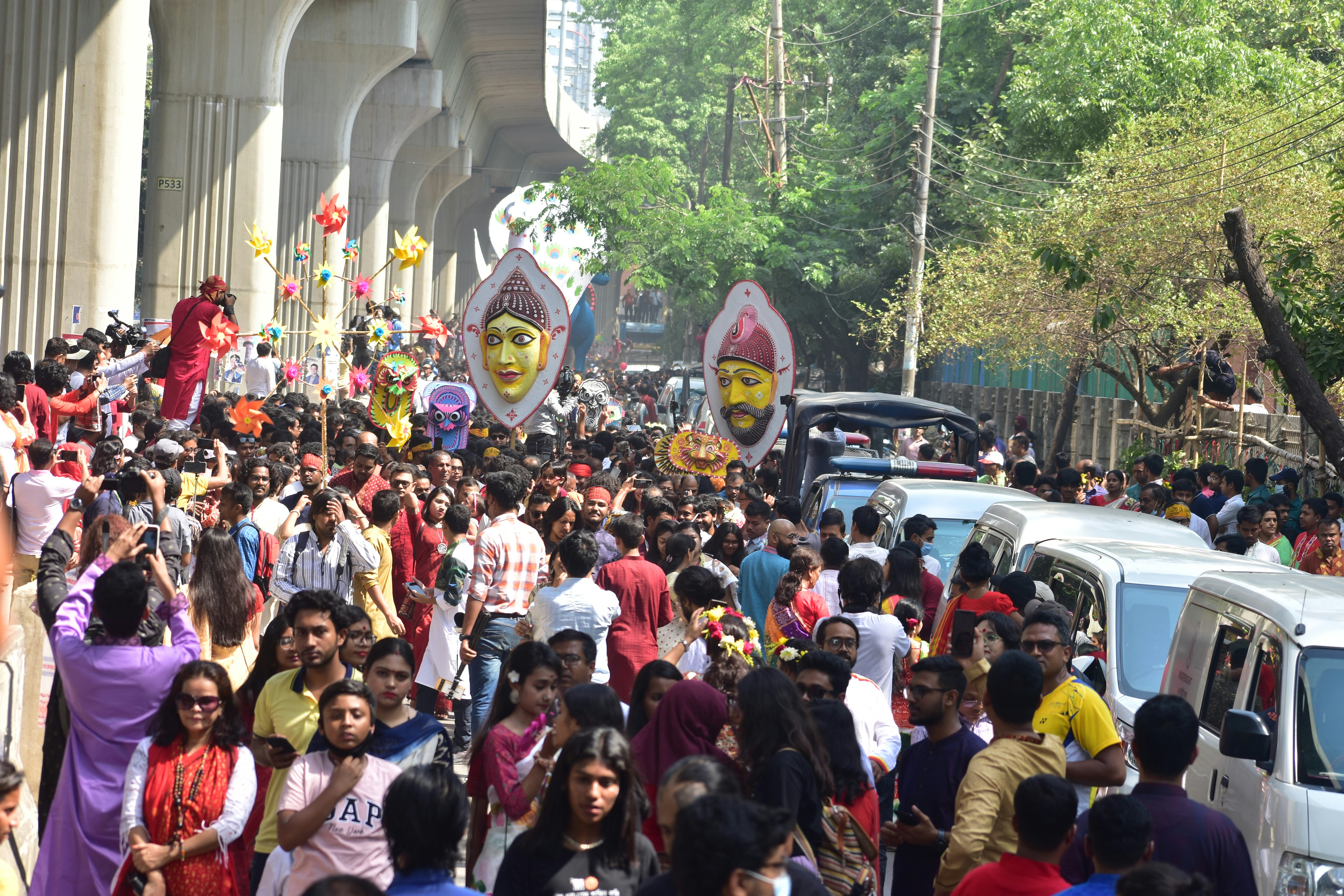 Crowd celebrating a festival with large masks onlooking heads.