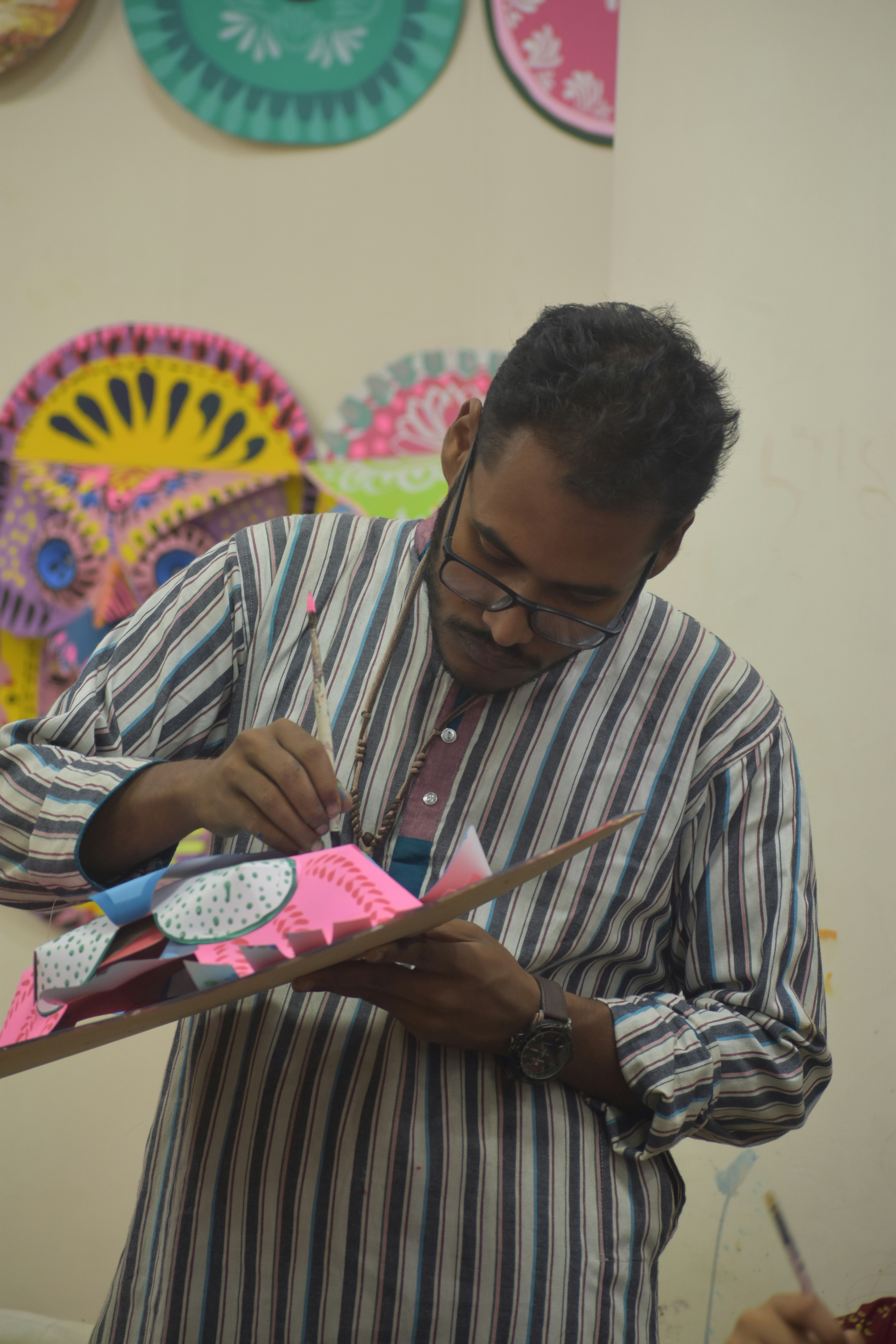 Man painting a colorful craft with brushes and paint.
