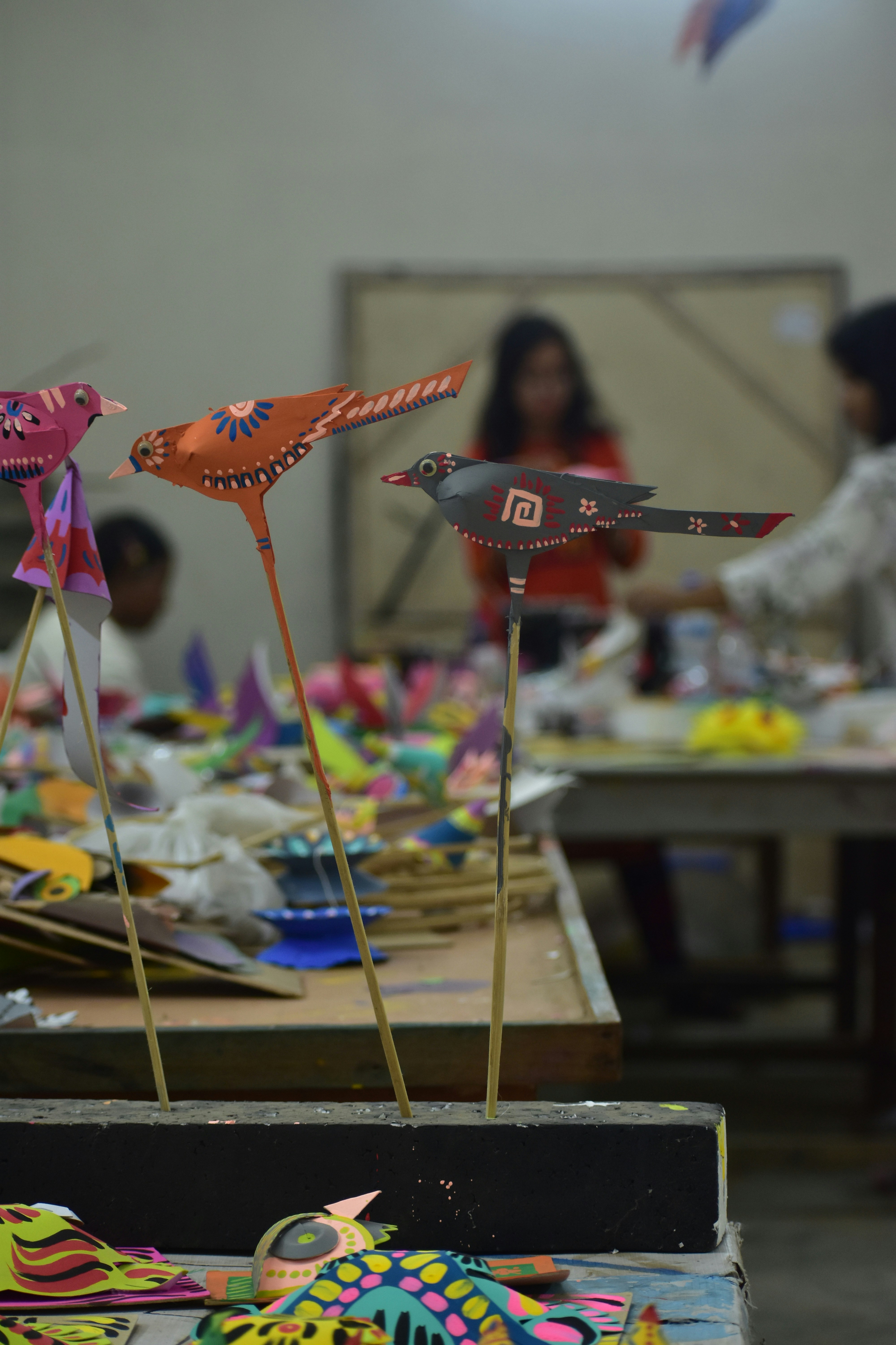 Colorful handcrafted birds on sticks in workshop