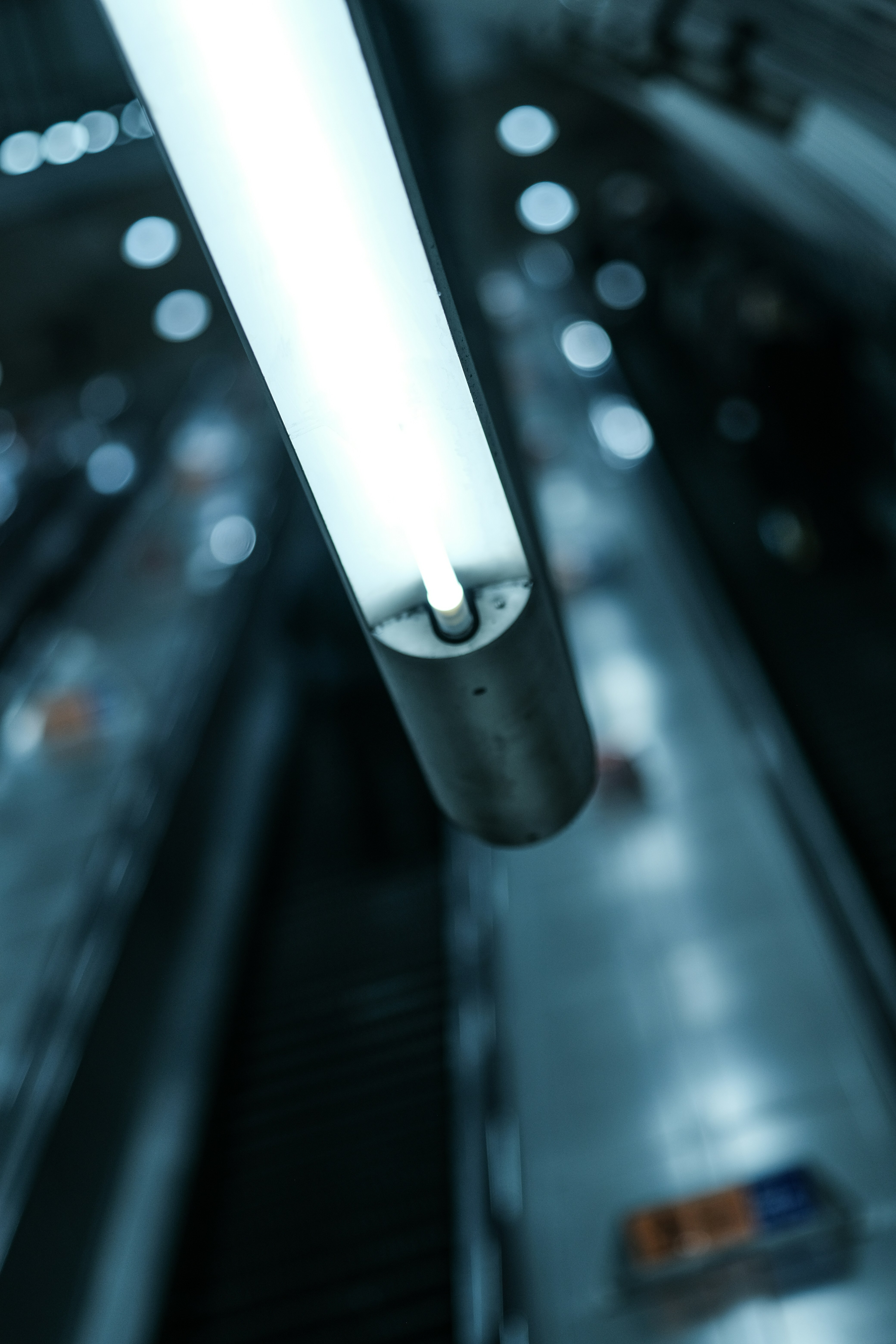 Bright fluorescent light above blurred escalators