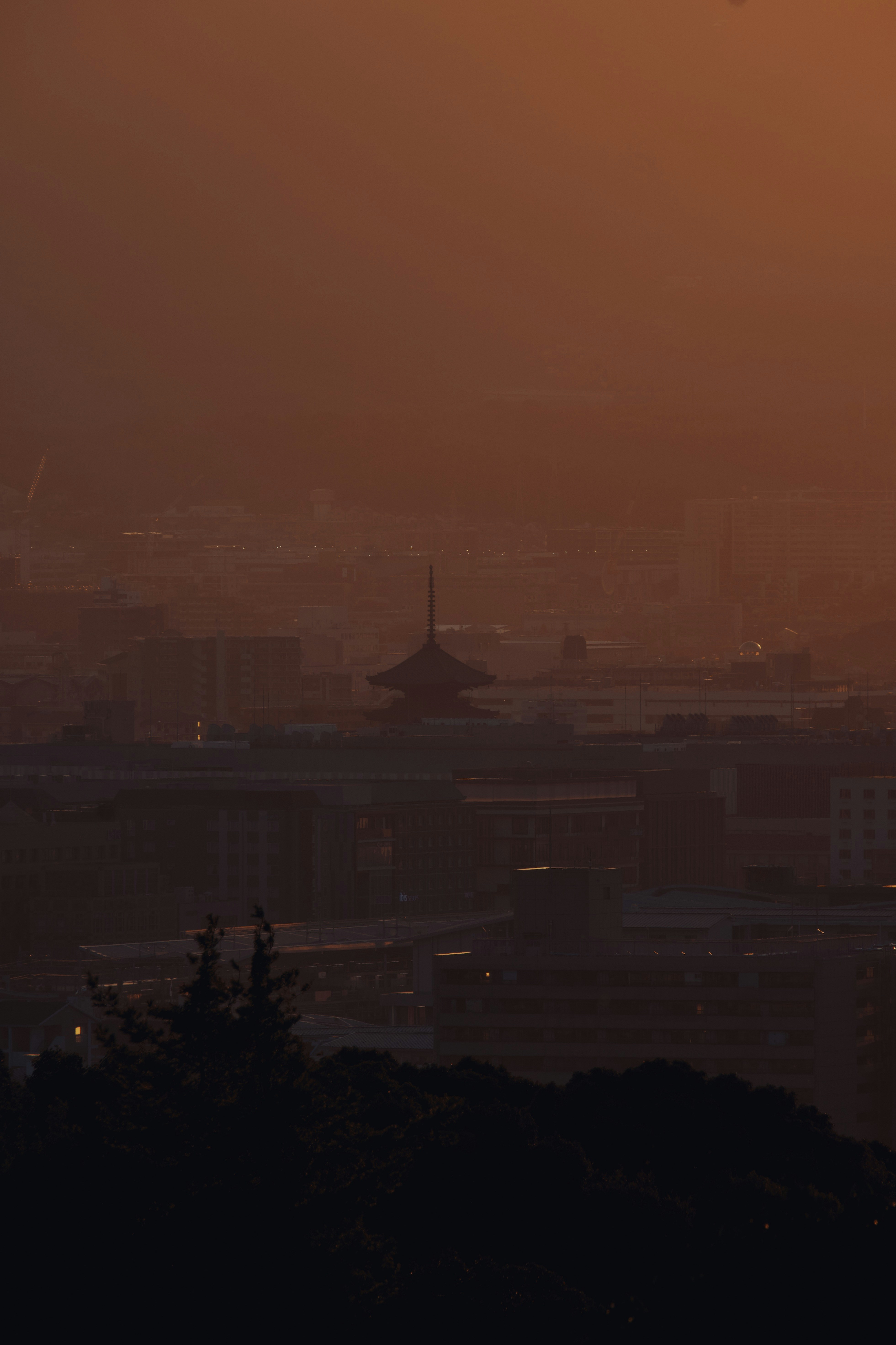 City skyline at sunset with pagoda silhouette.