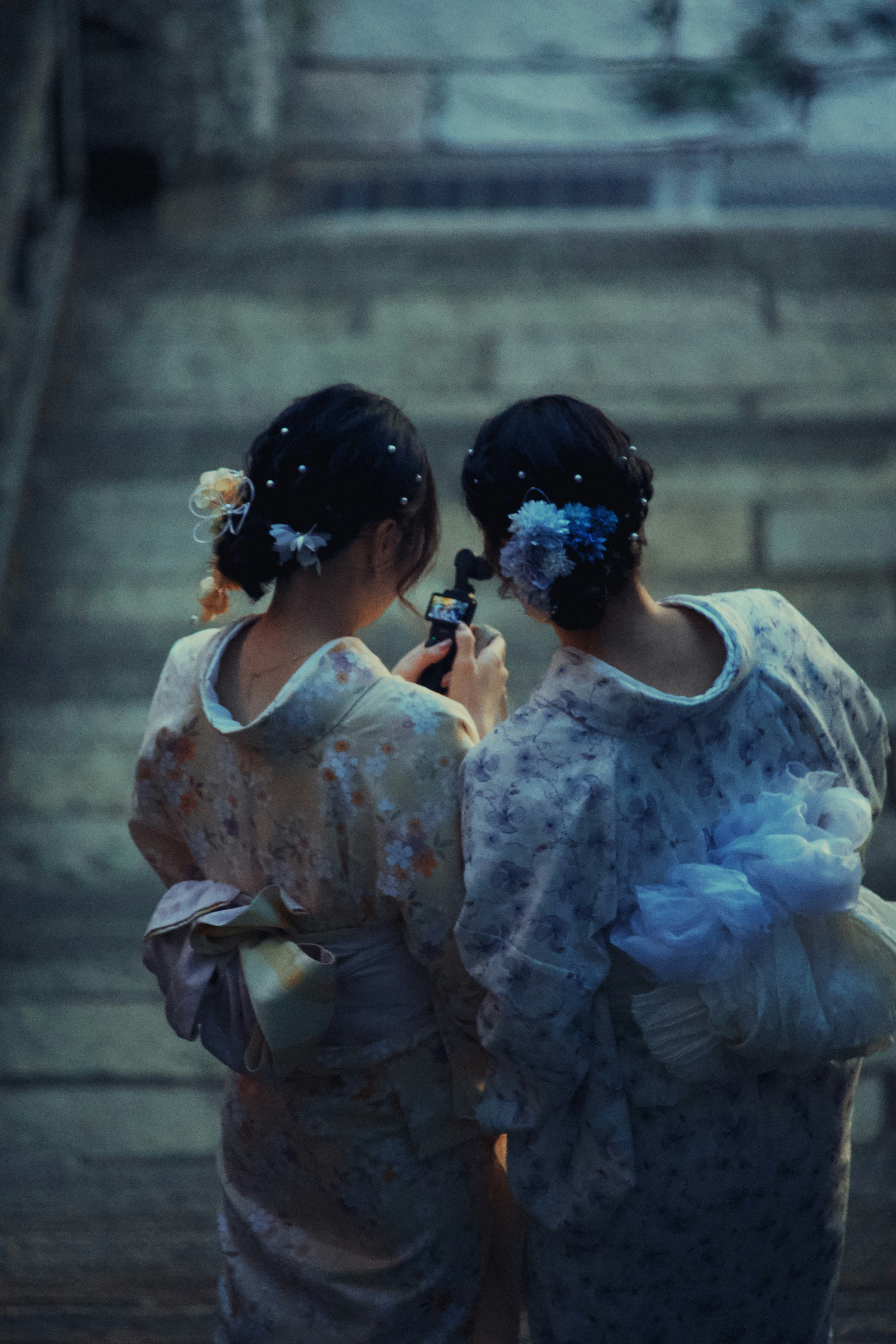 Two women in kimonos looking at a phone