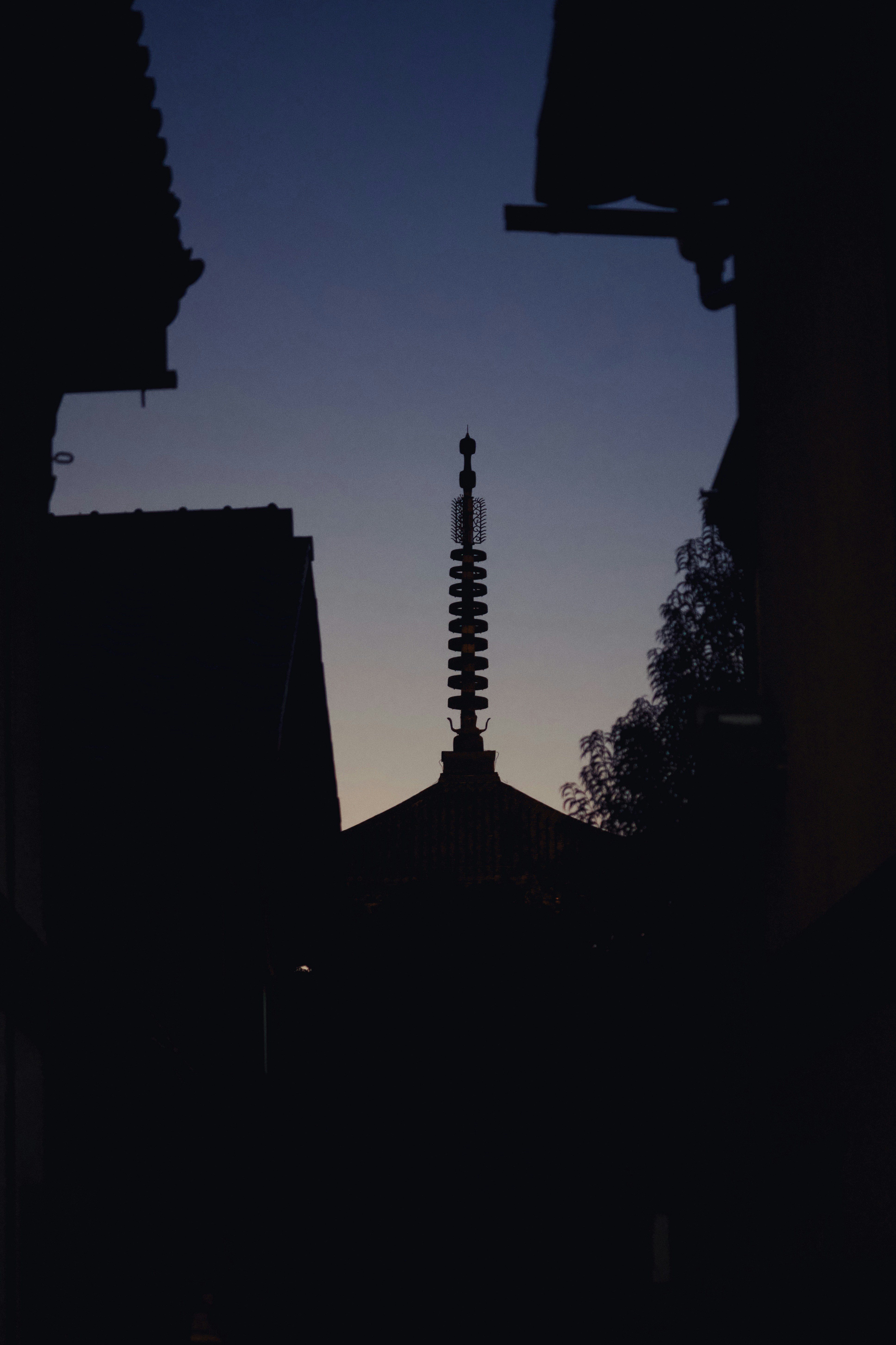 Silhouette of a temple spire against twilight sky.