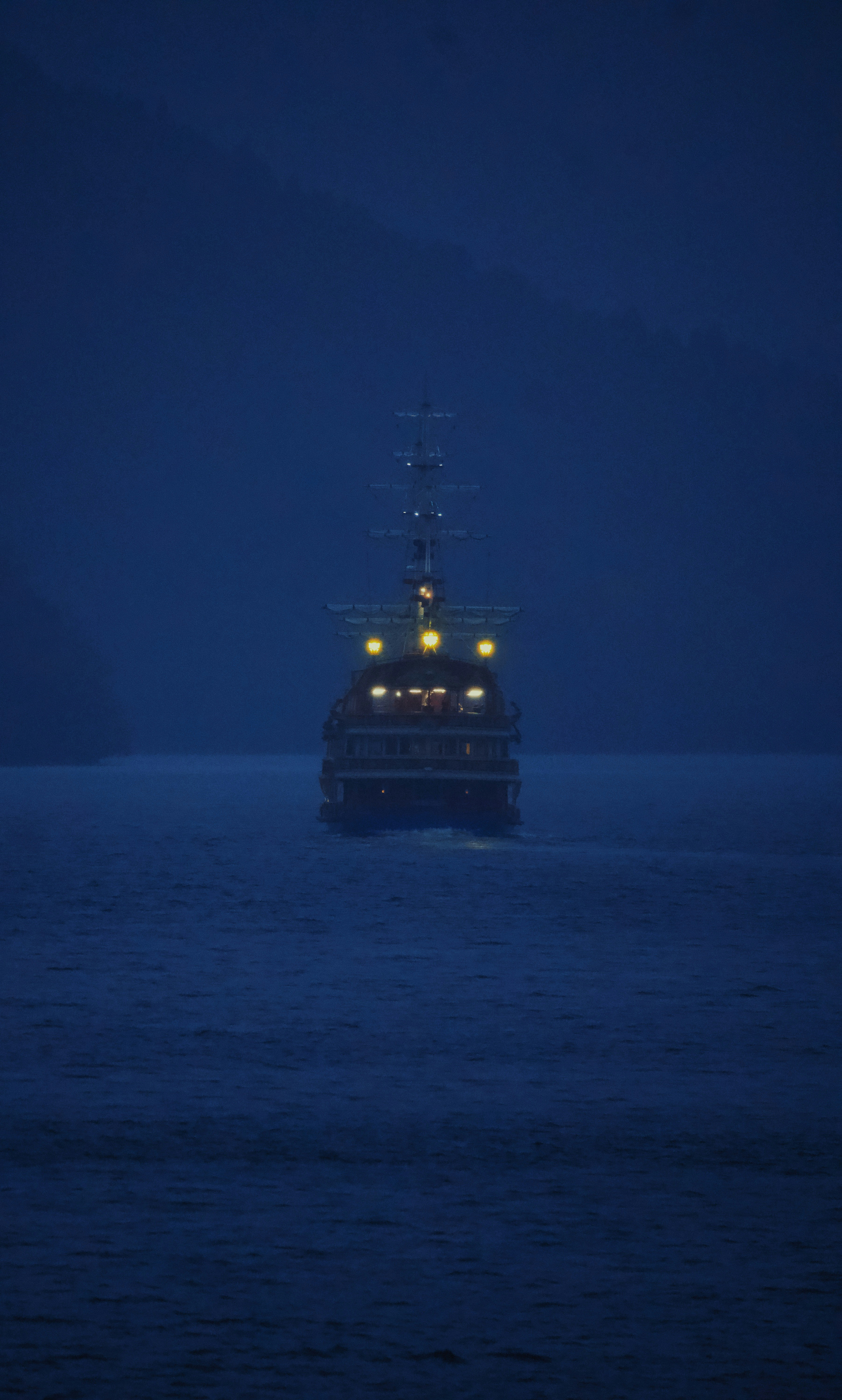 A ship sails on the ocean at night.