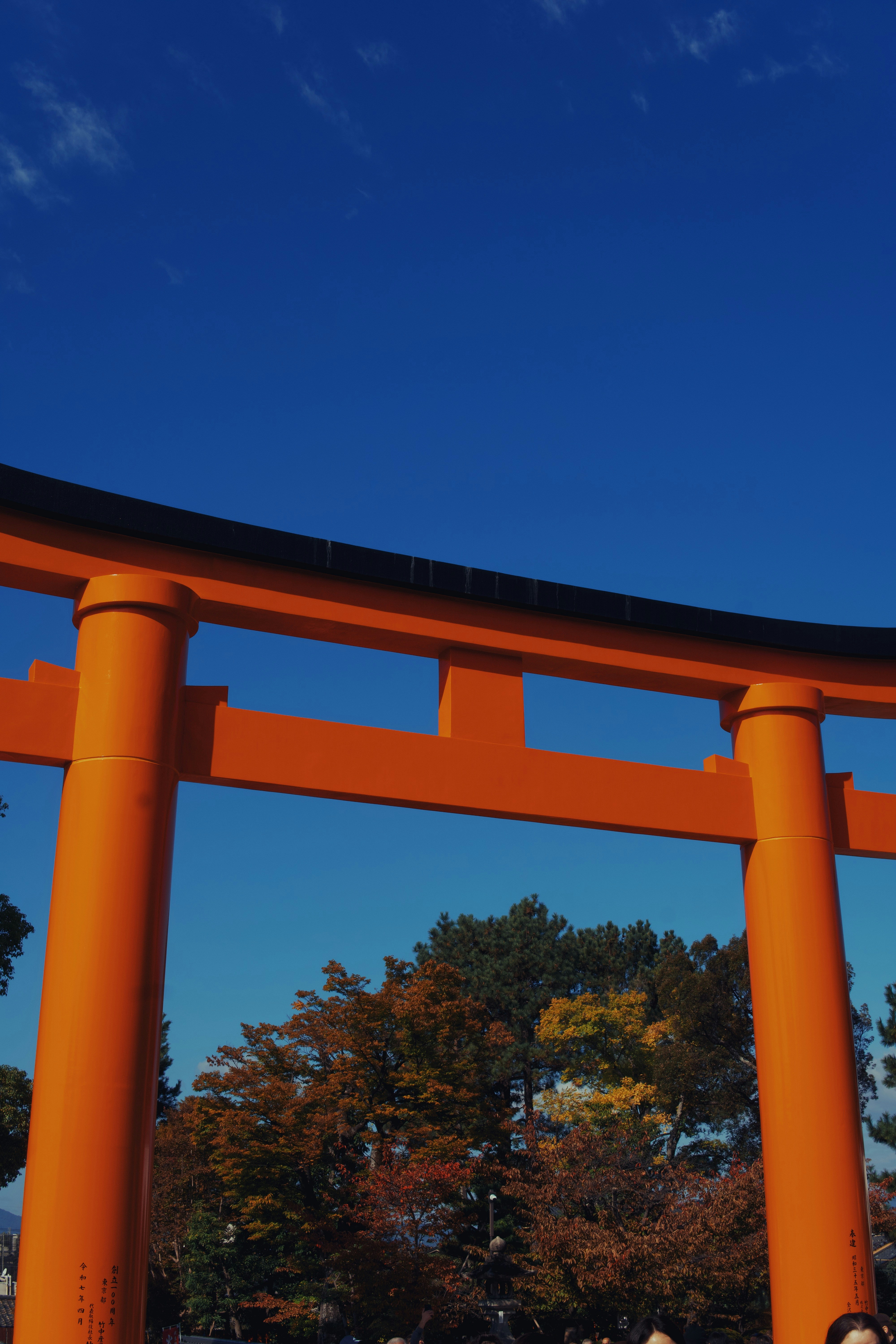 Bright orange torii gate against a clear blue sky.