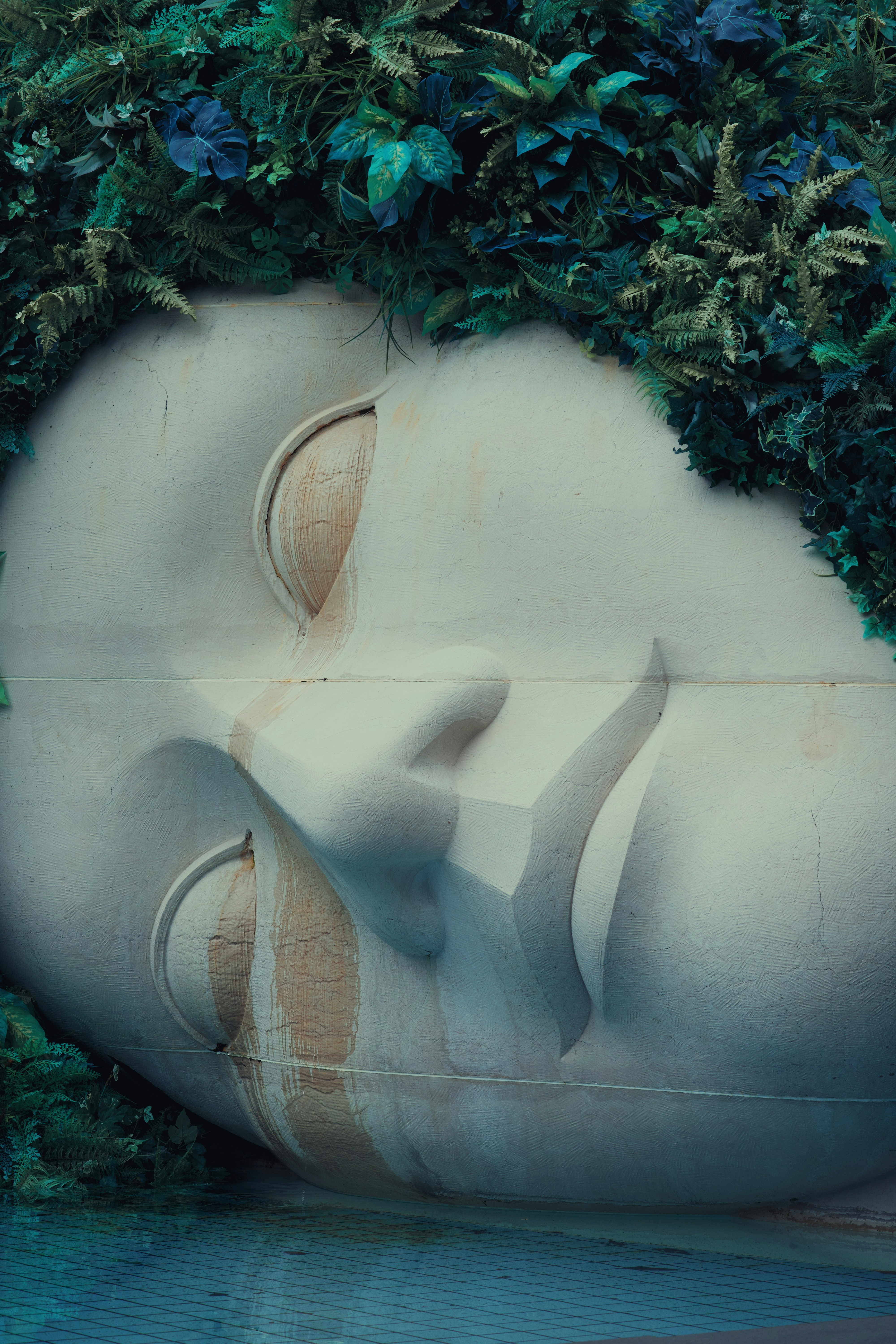Giant serene face sculpture adorned with lush greenery