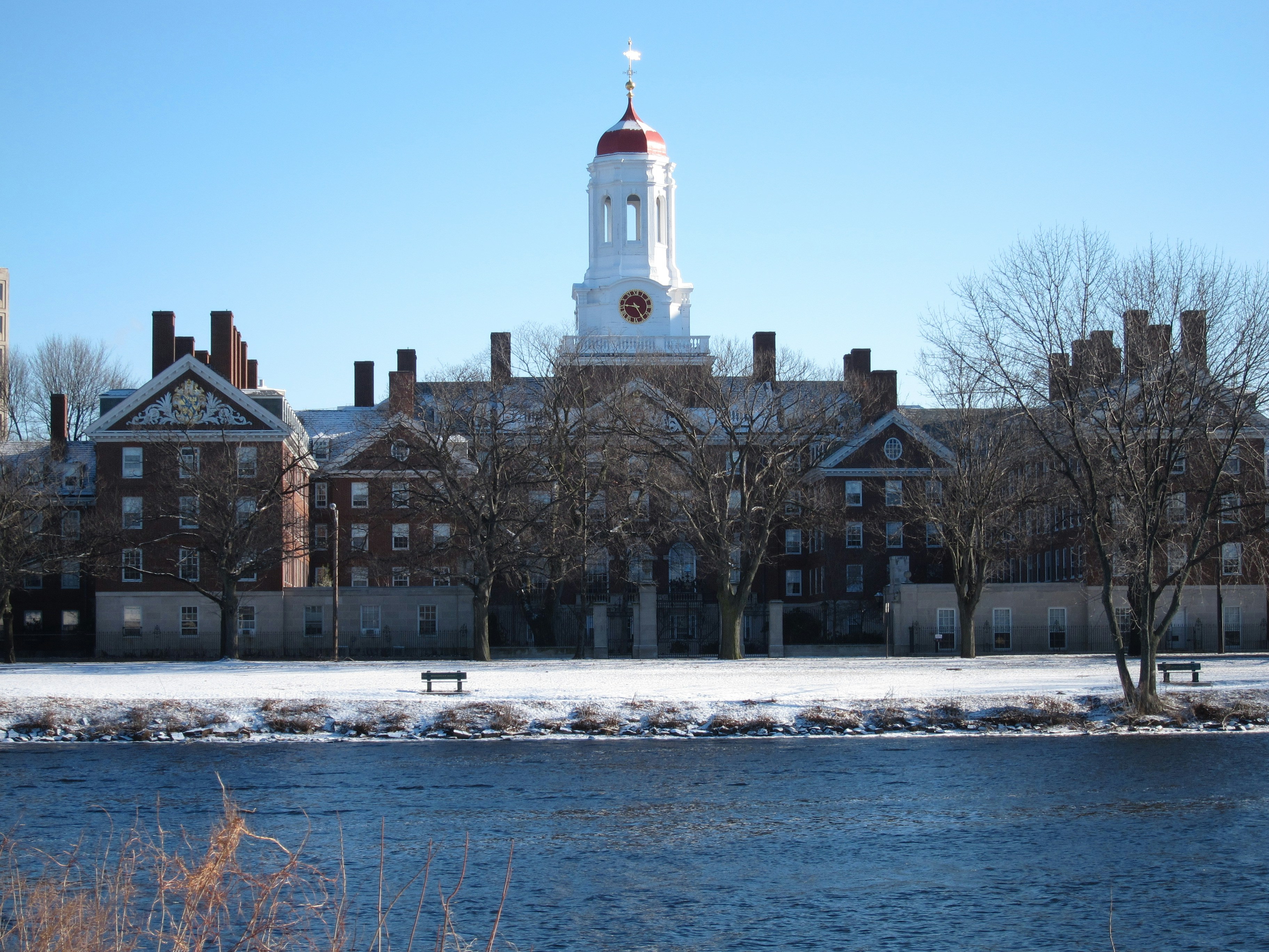 Snowy campus buildings with a river in foreground.