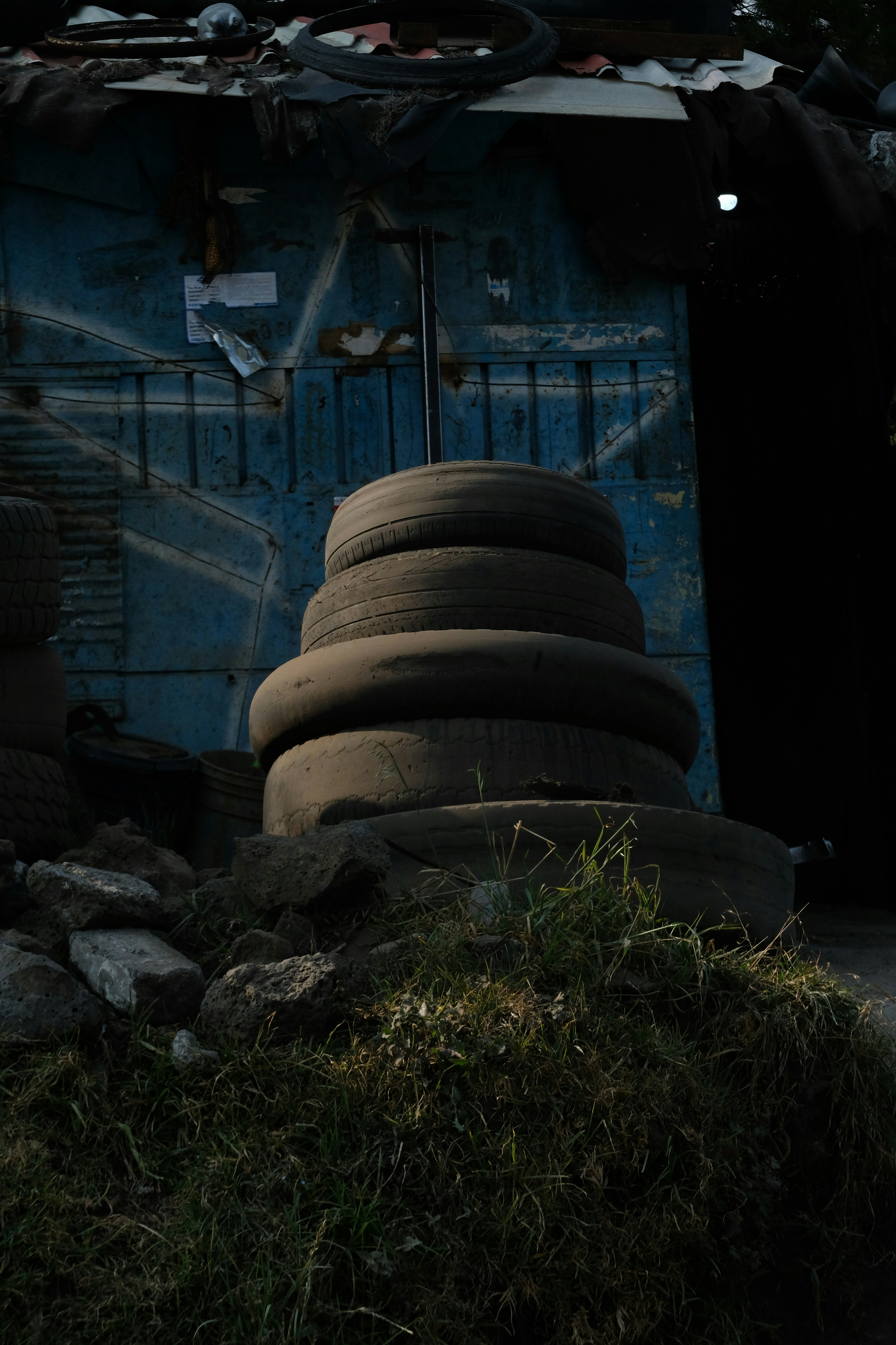 Stack of old tires in front of a blue structure.