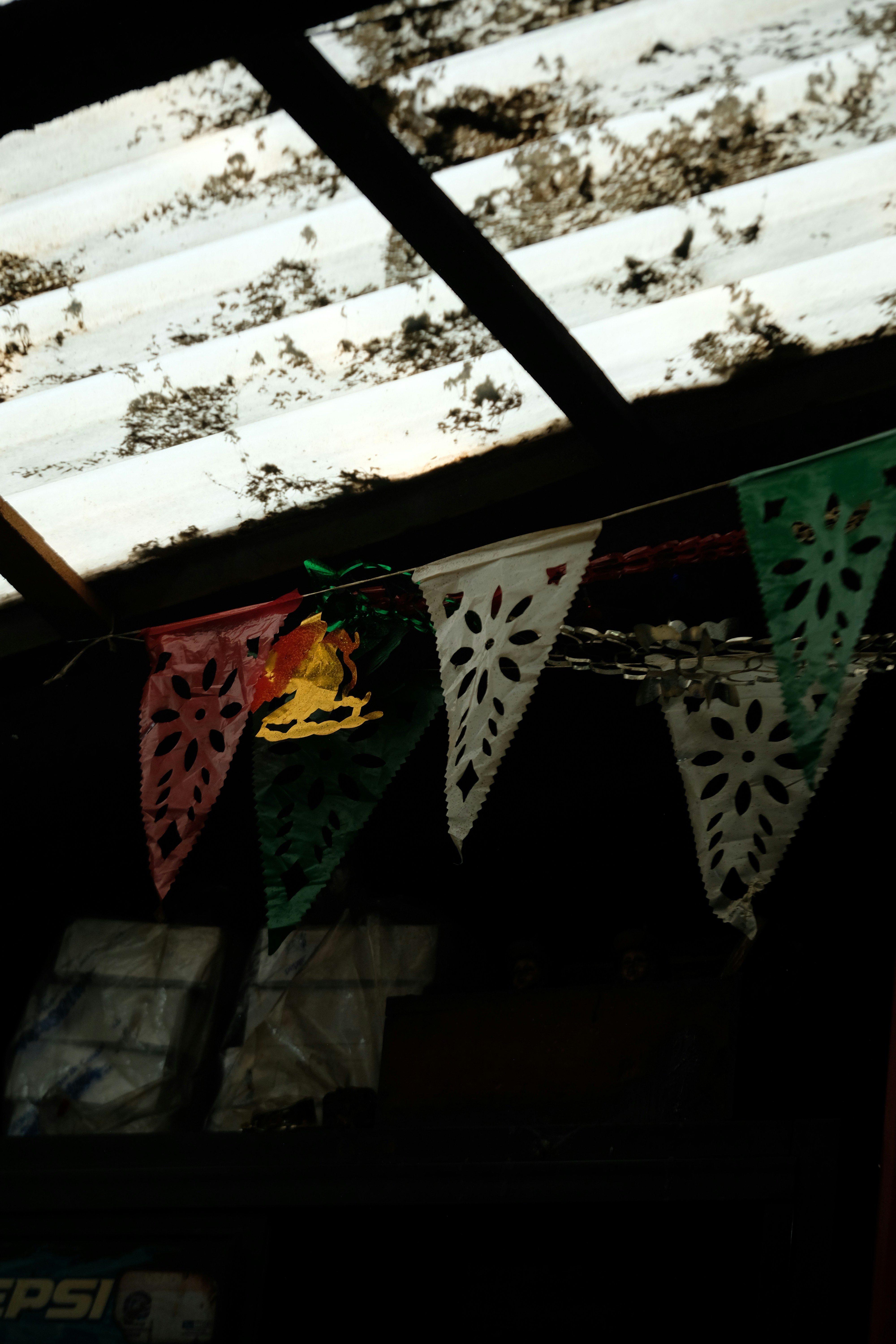 Colorful papel picado banners hang under corrugated roof.