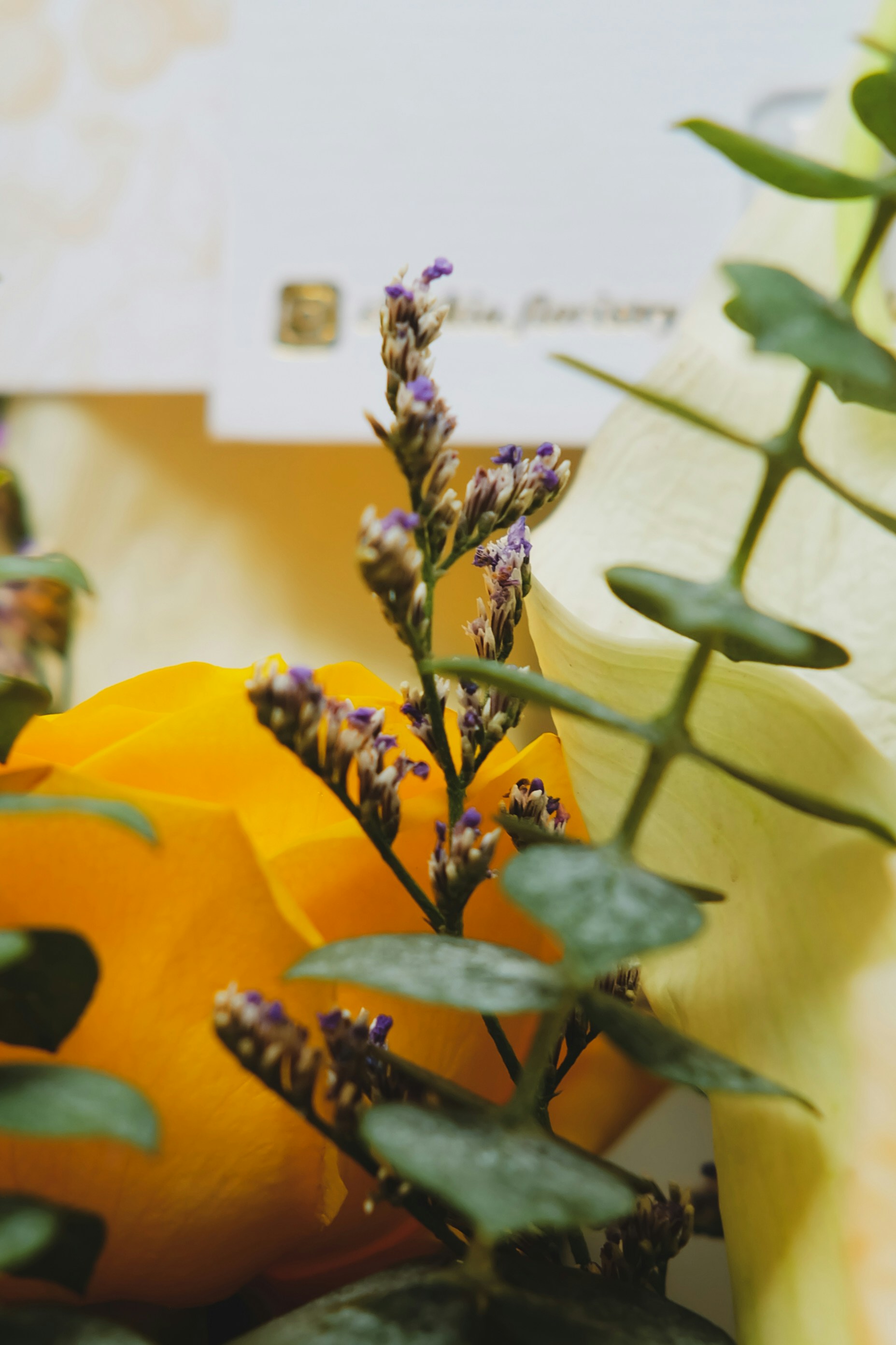 Close-up of a yellow rose with delicate purple flowers.