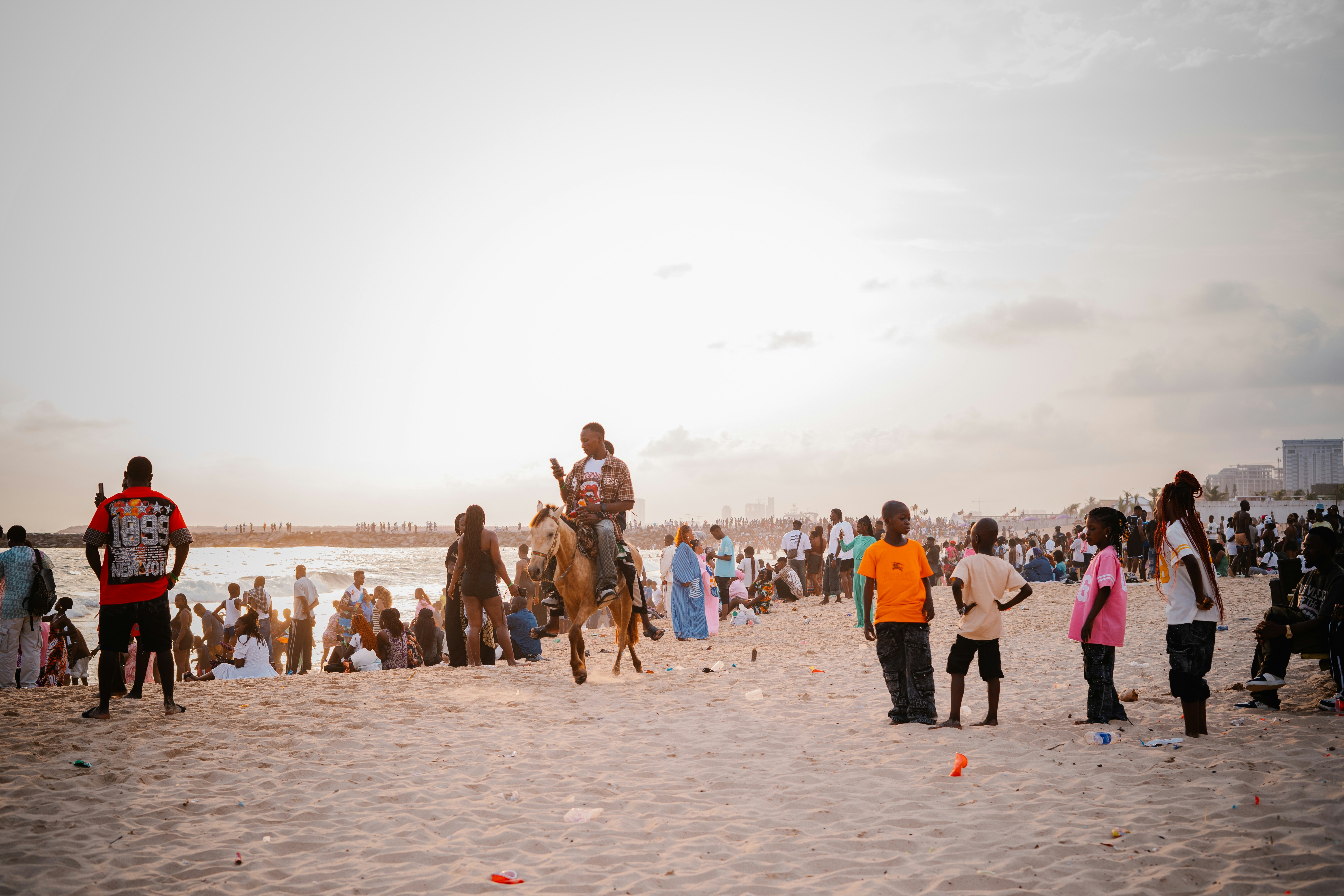 People on a beach with a man riding a camel.