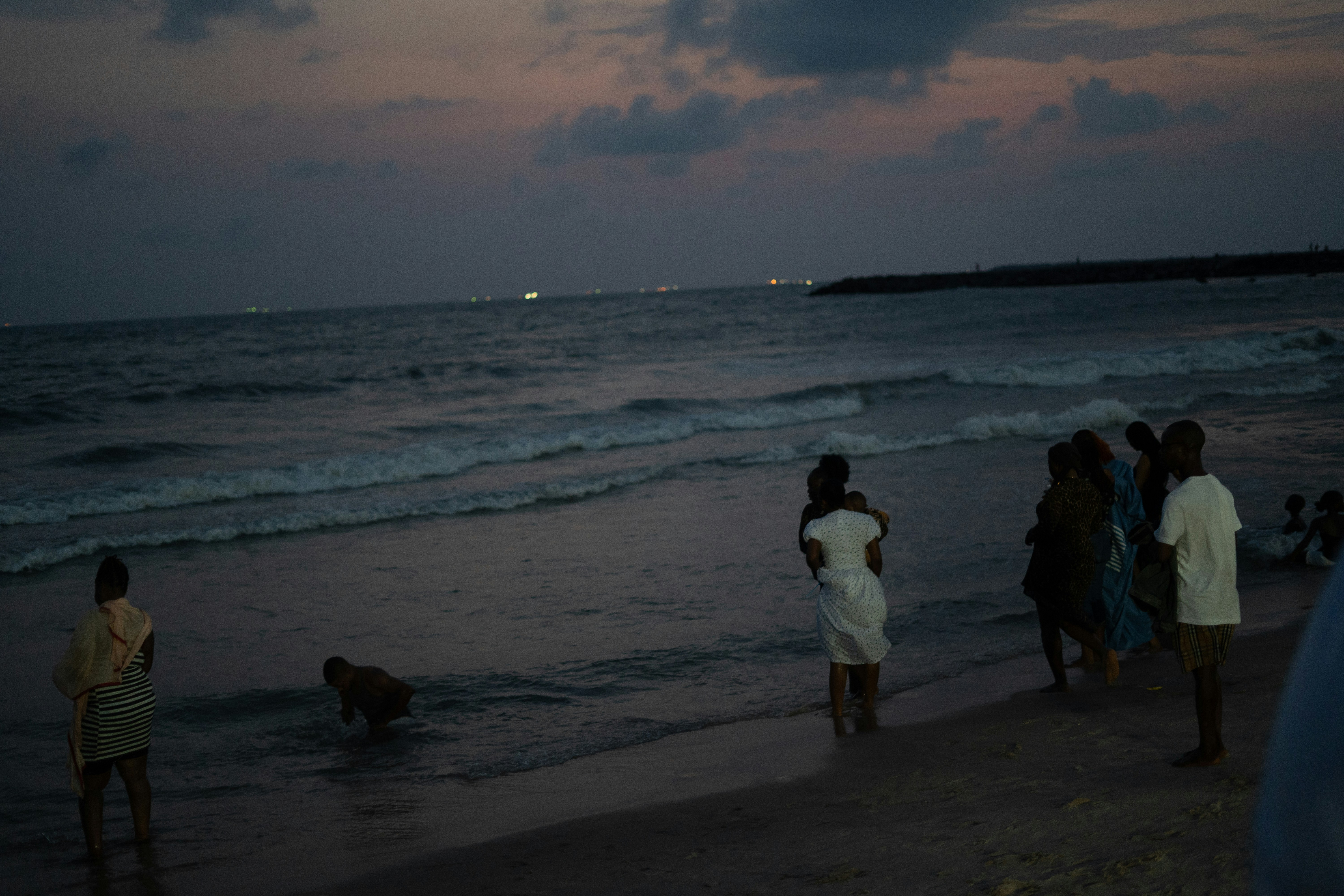 People gather on a beach at dusk