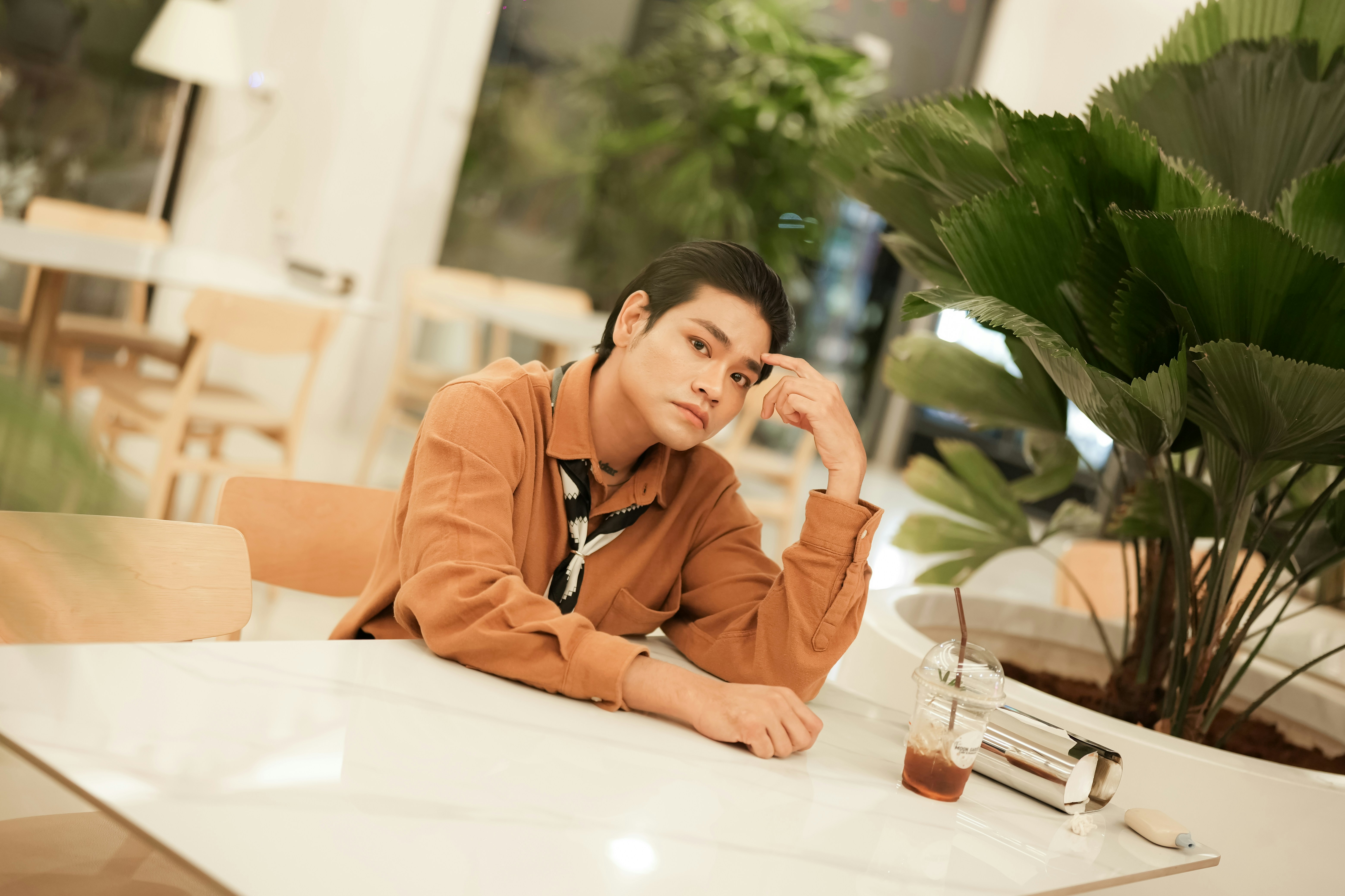 Jeune homme assis à une table avec des plantes.