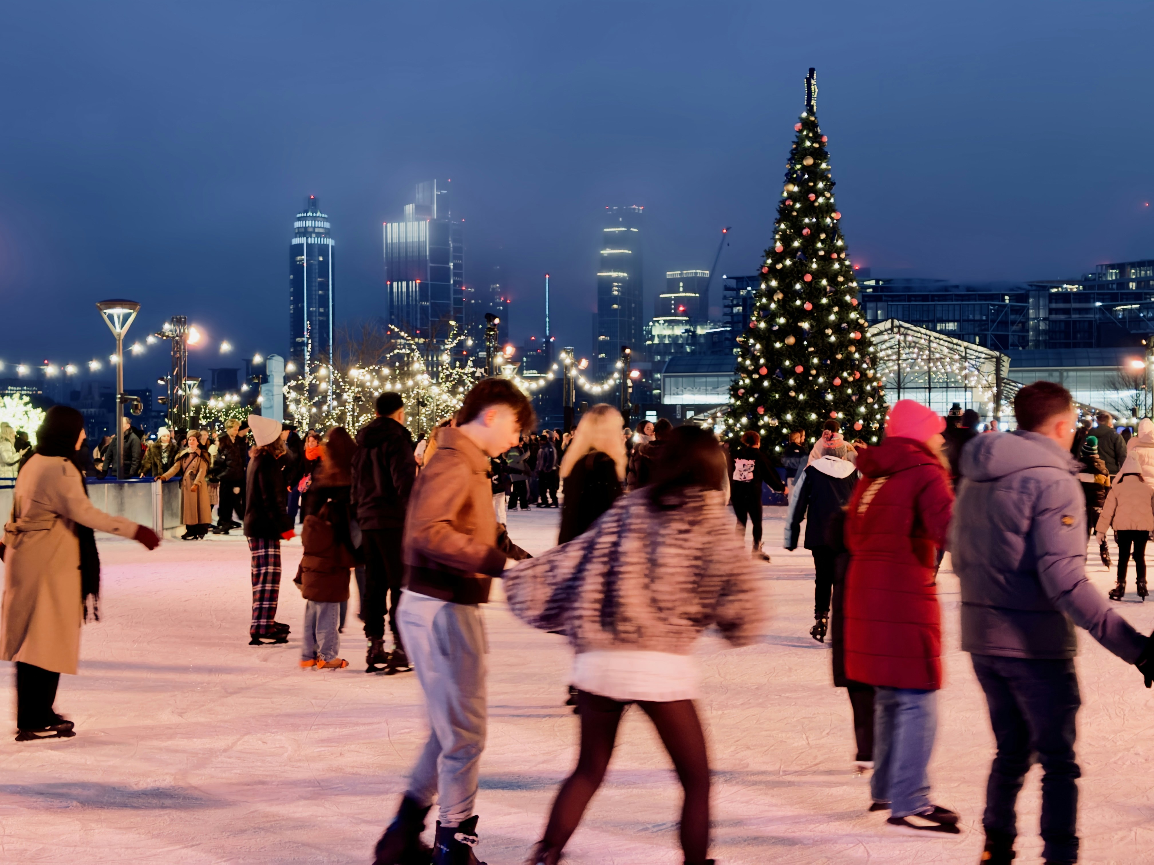 People ice skating near a christmas tree at night
