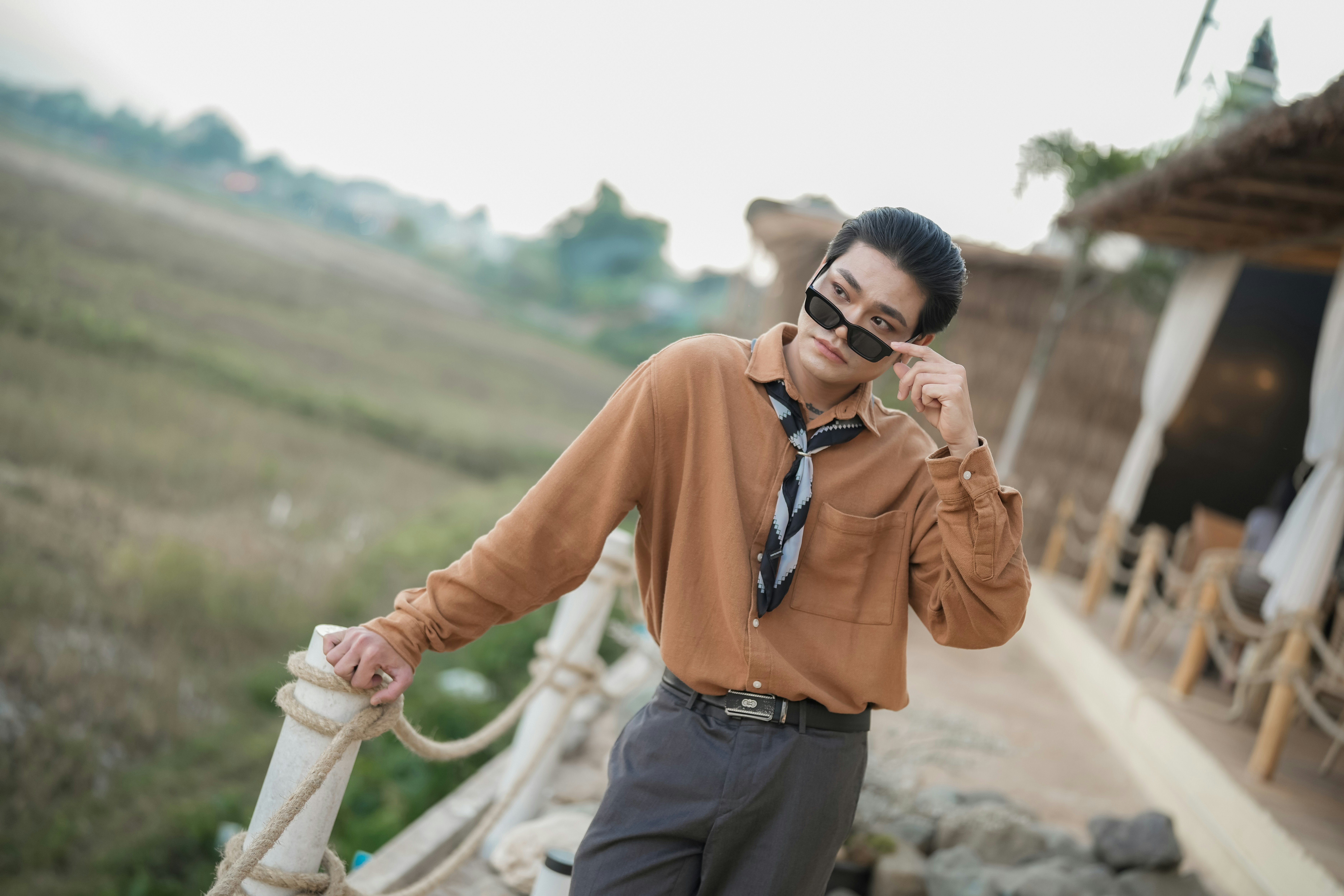 Man in sunglasses and brown shirt posing outdoors