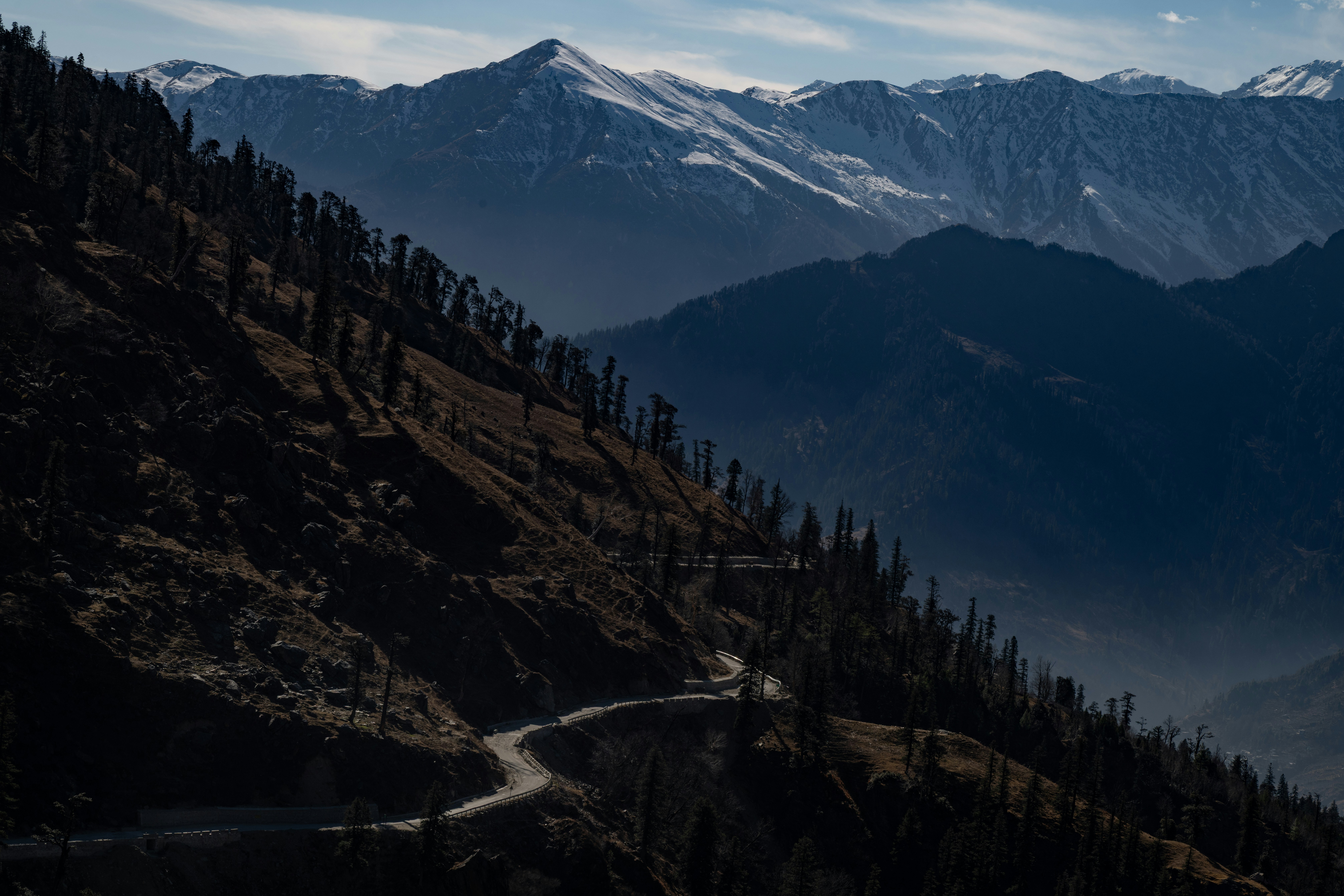 Eine gewundene Bergstraße durch dunkle, bewaldete Hänge.