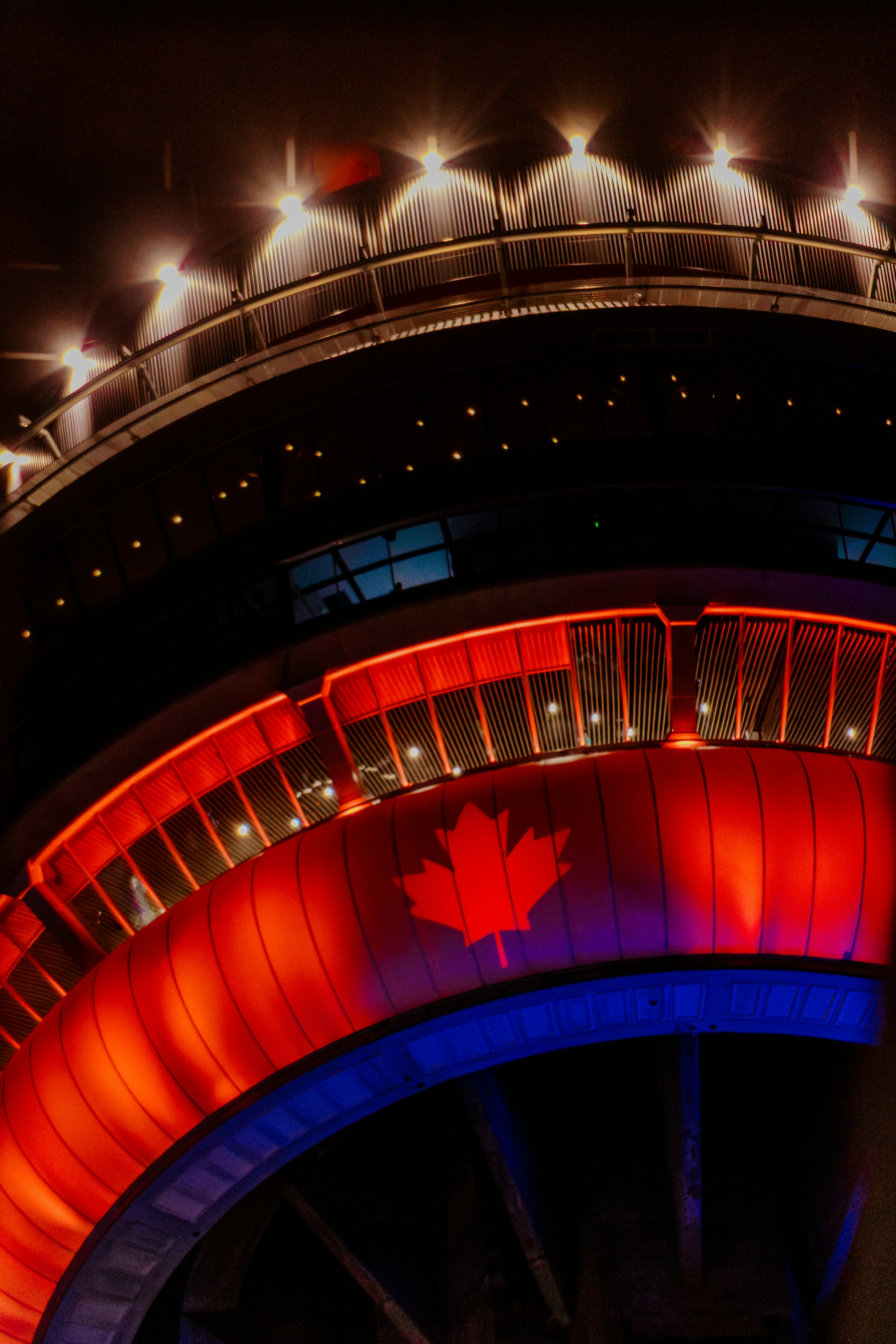 Canadian flag illuminated on a modern building at night