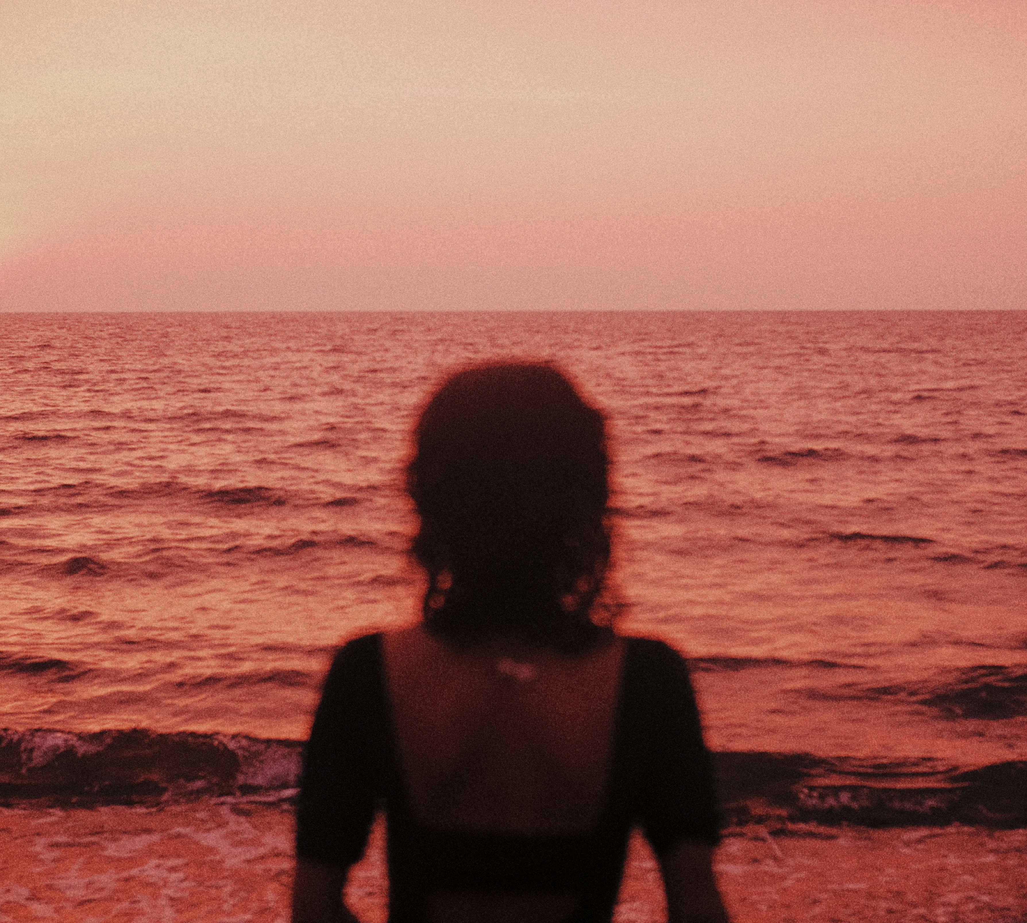 Frau, die bei Sonnenuntergang aufs Meer blickt