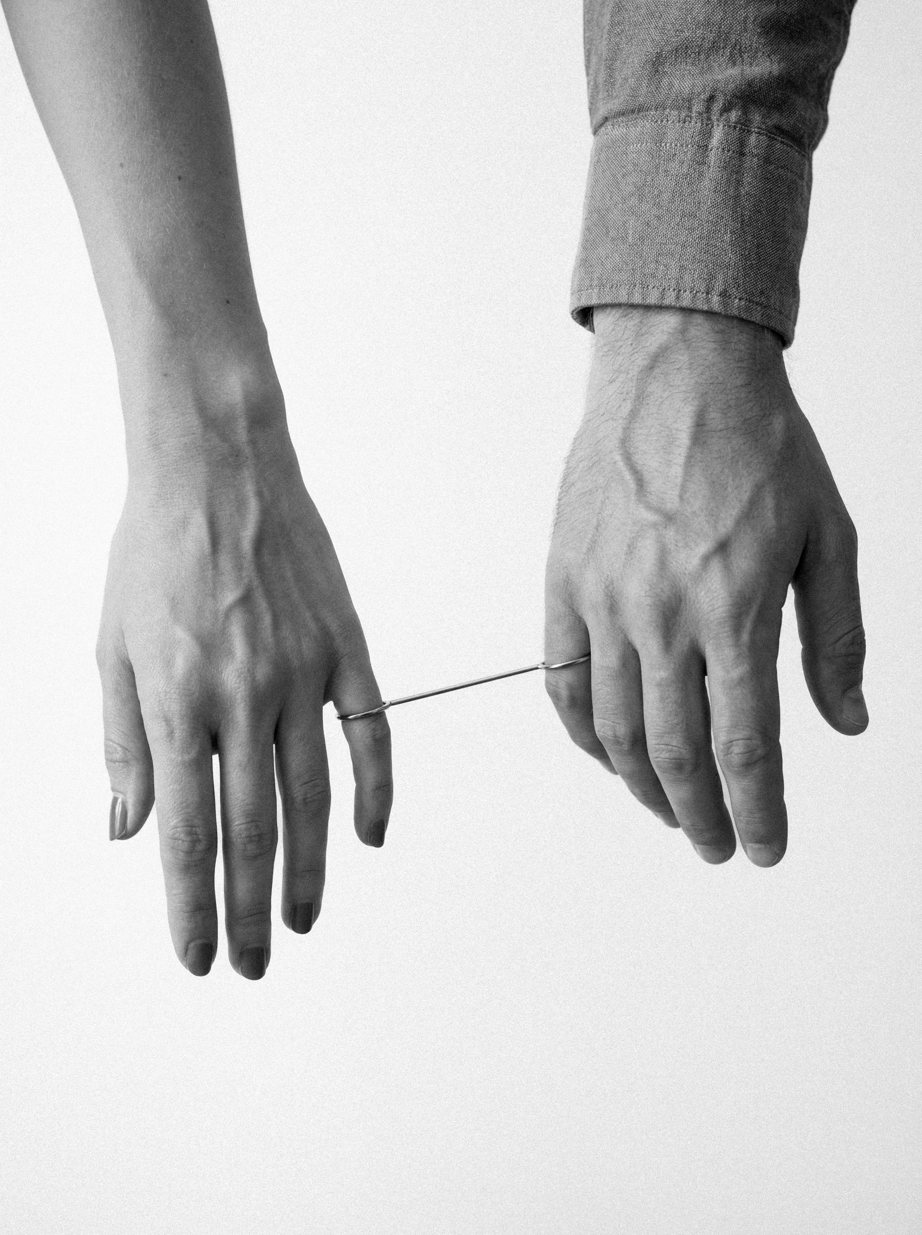 Two hands connected by a thin wire.