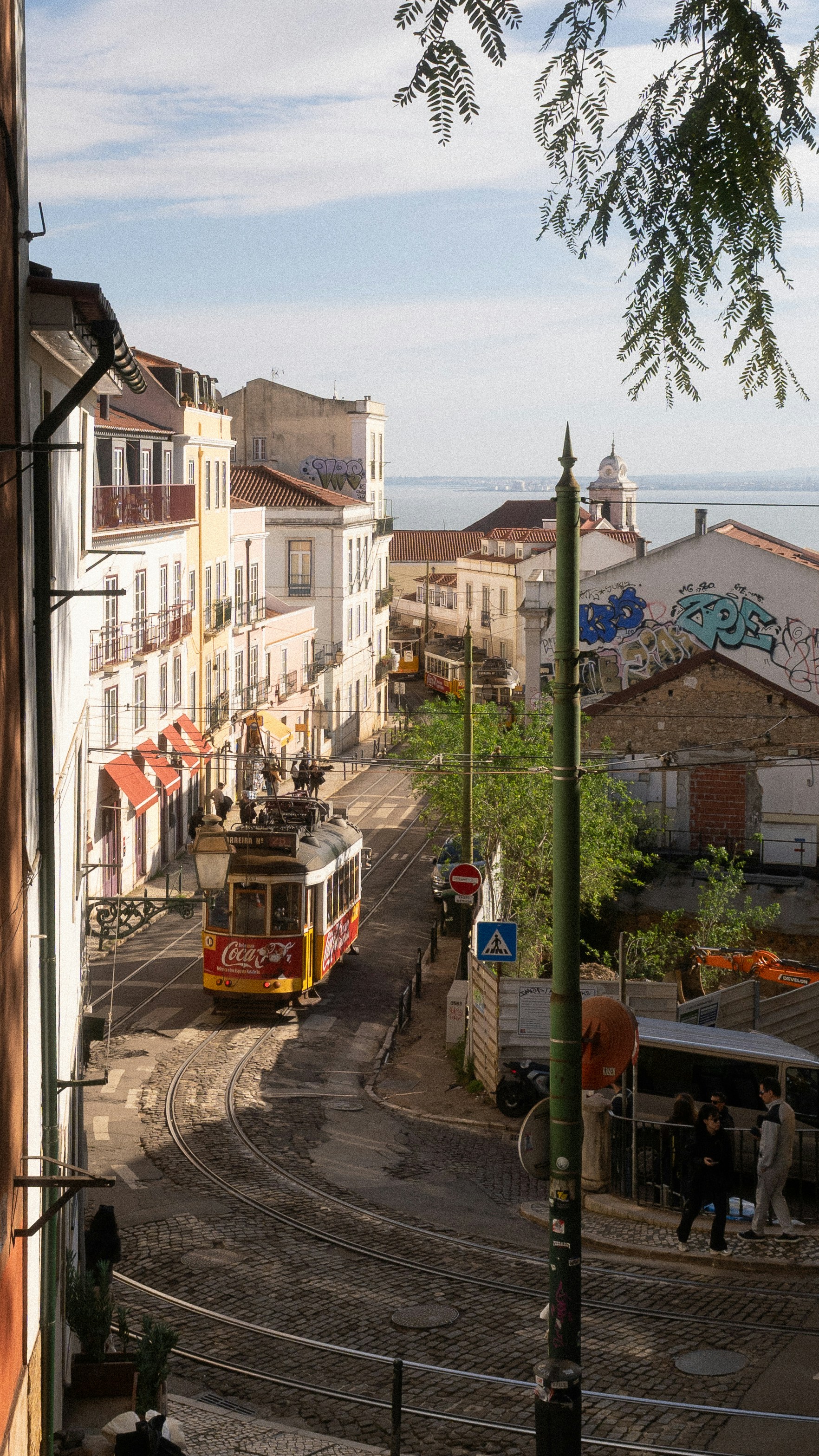 A vintage tram travels down a cobblestone street.