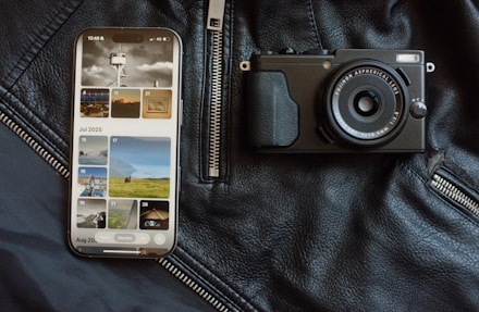 Smartphone and camera on black leather