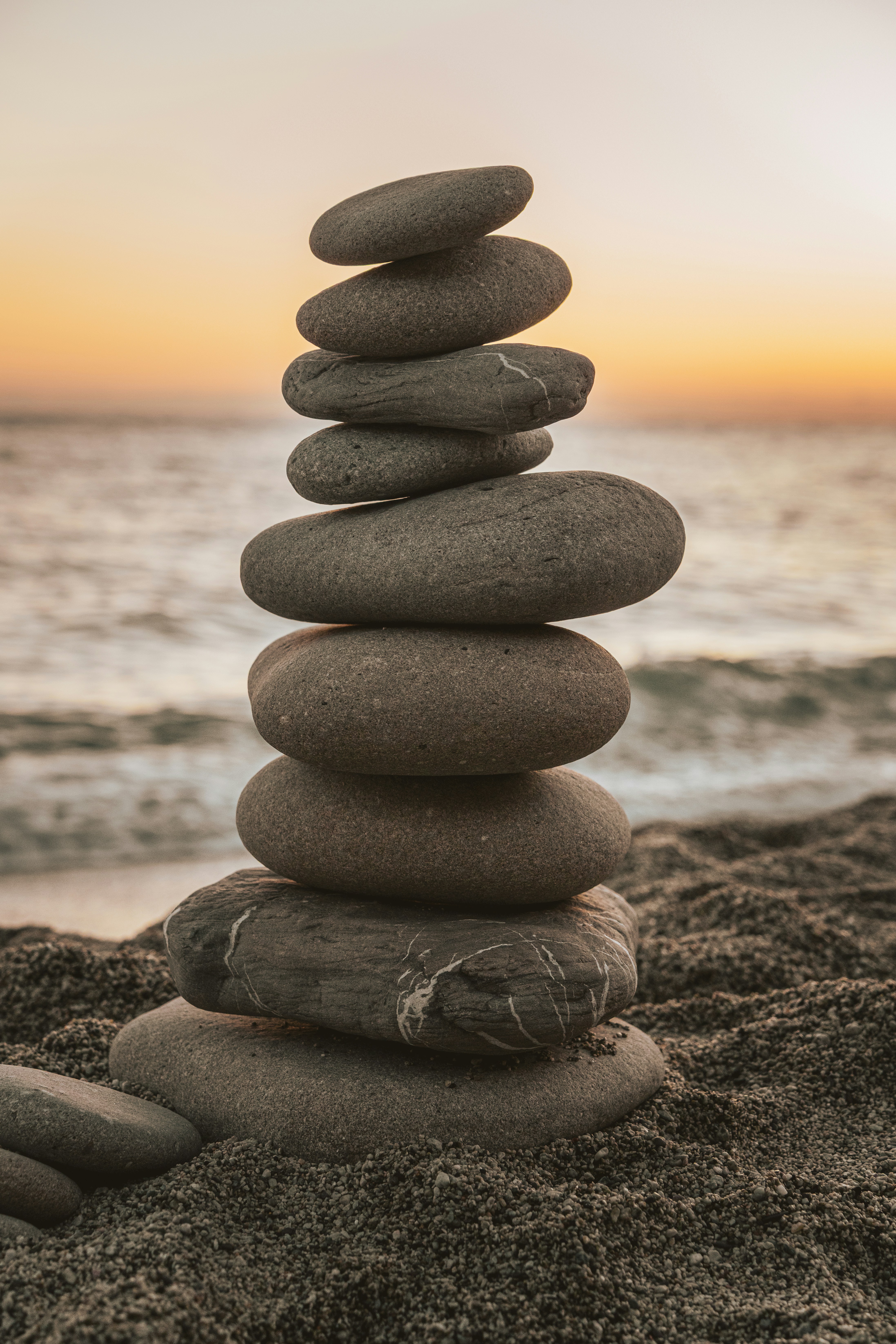 Stack of balanced stones on a sandy beach at sunset