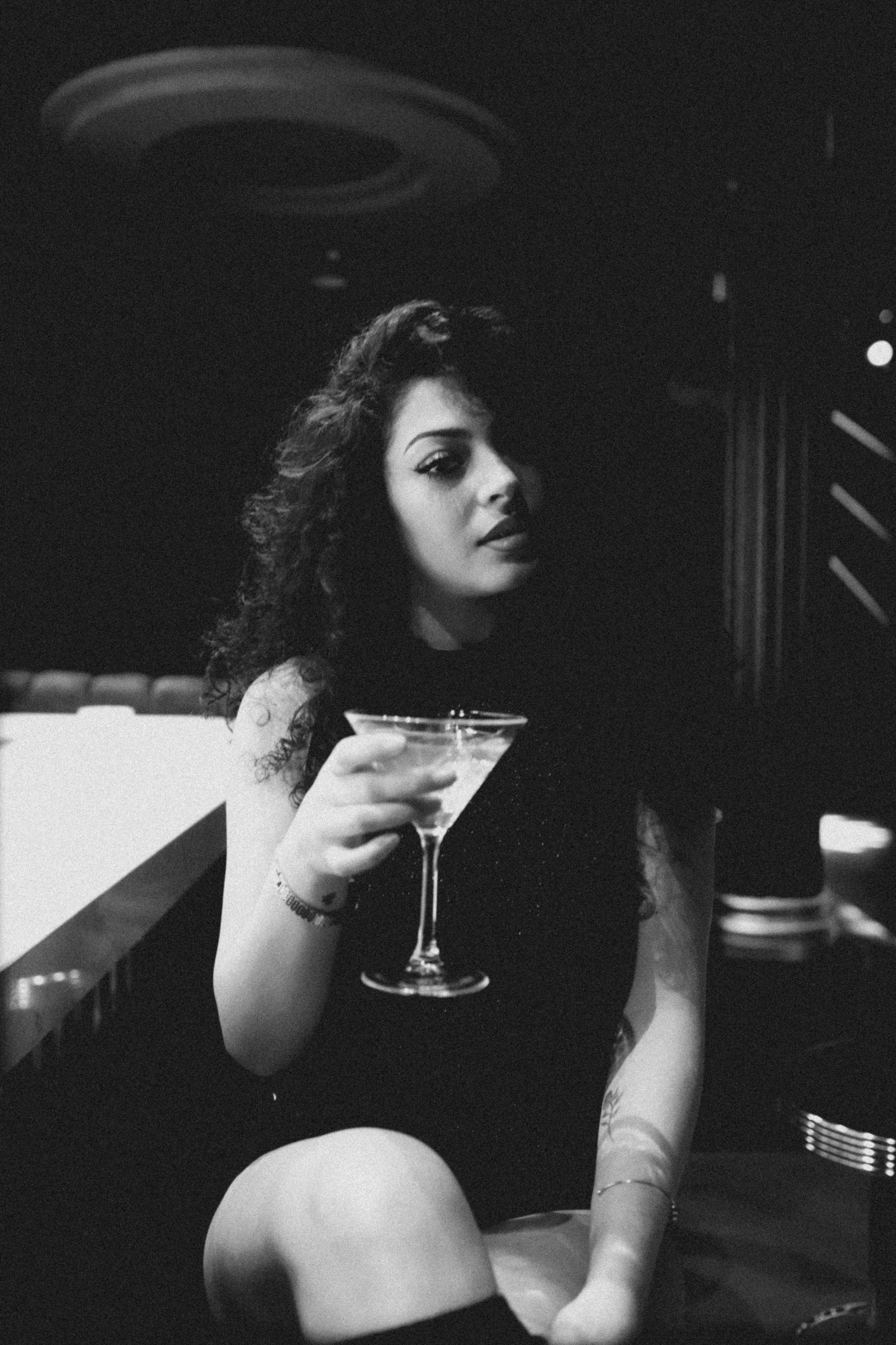Woman holding a martini in a dimly lit bar.