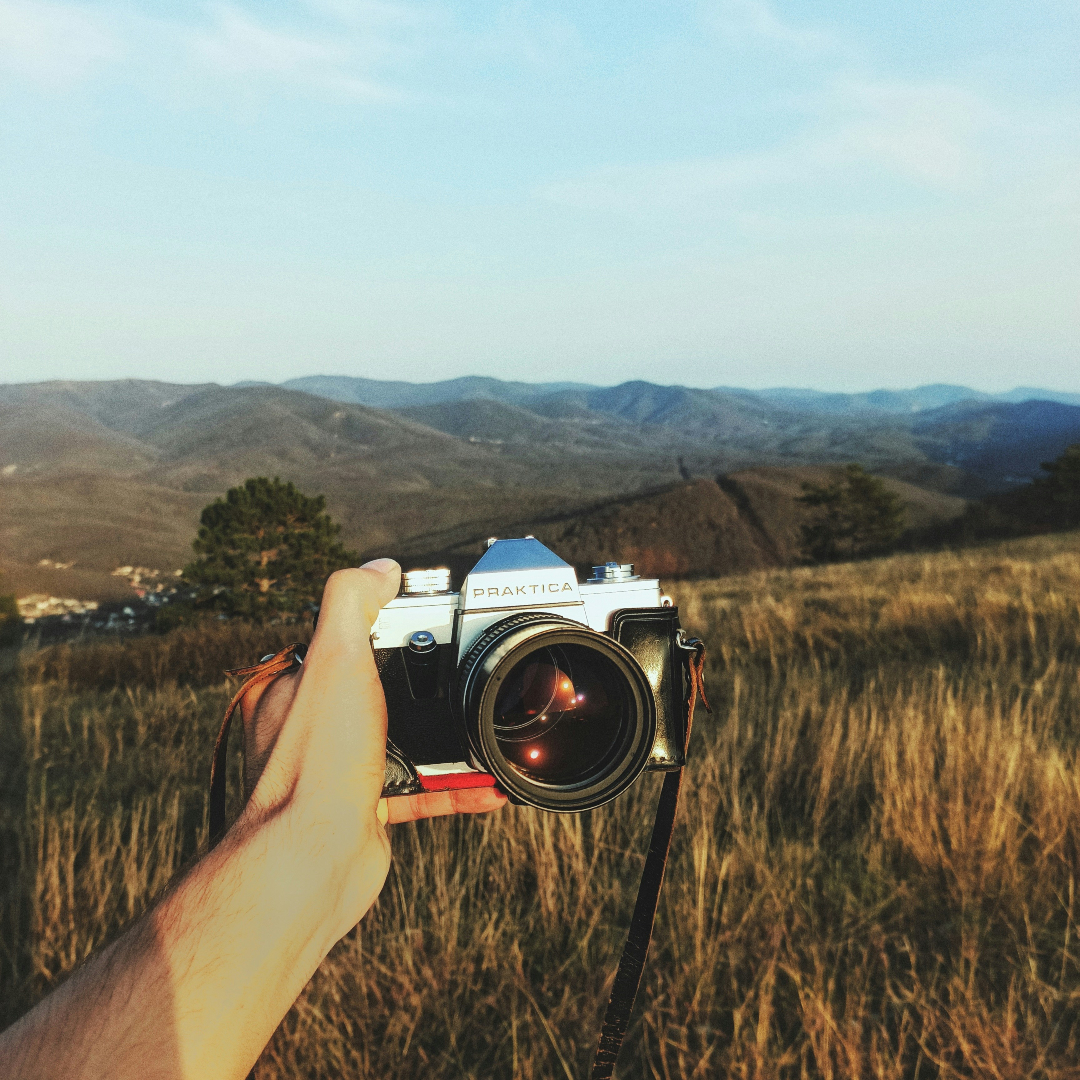Tenere la macchina fotografica vintage in un paesaggio erboso
