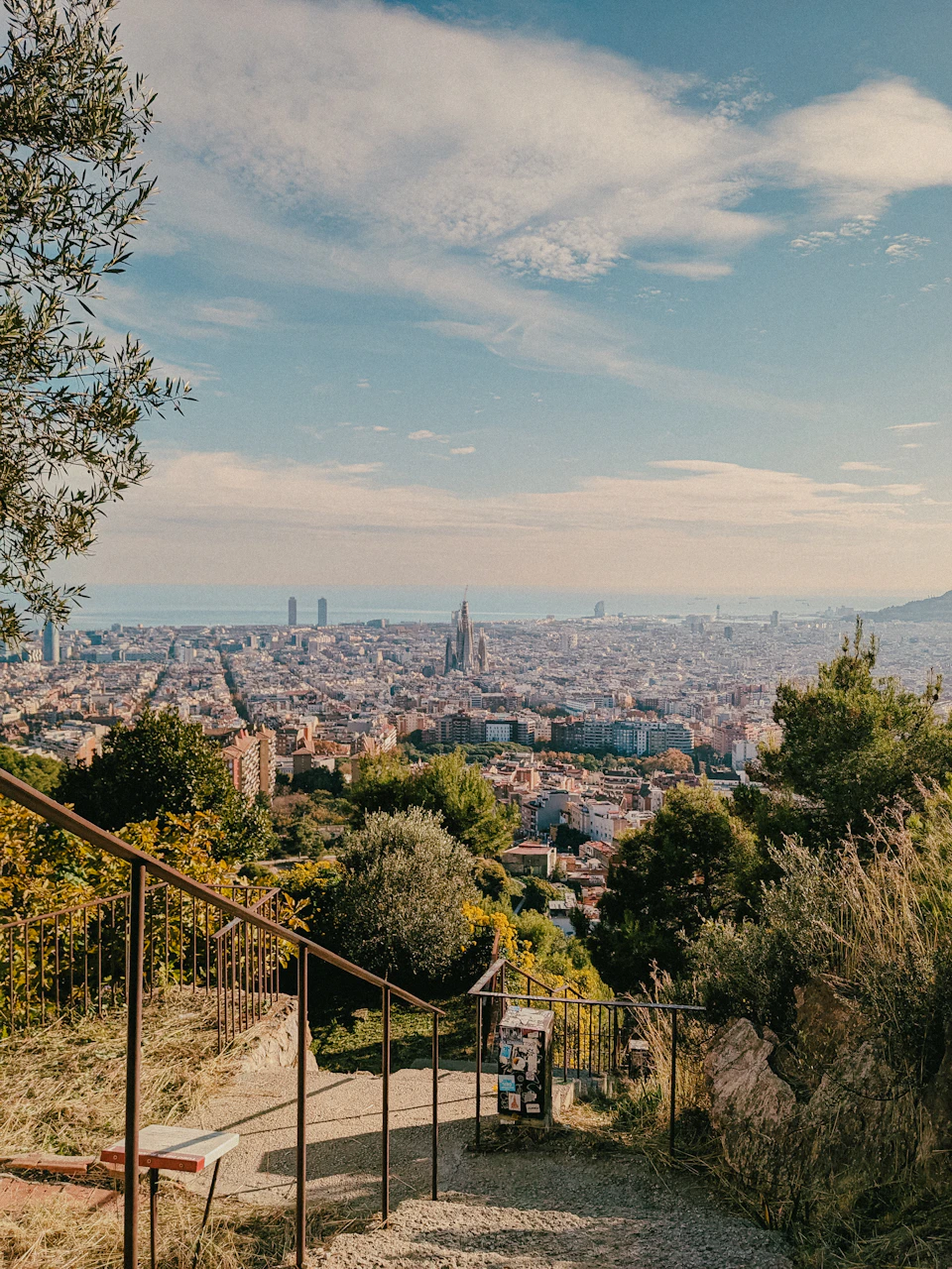 Panoramic view across Barcelona's rooftops and the Mediterranean from the elevated terraces of Park Güell on a clear spring afternoon