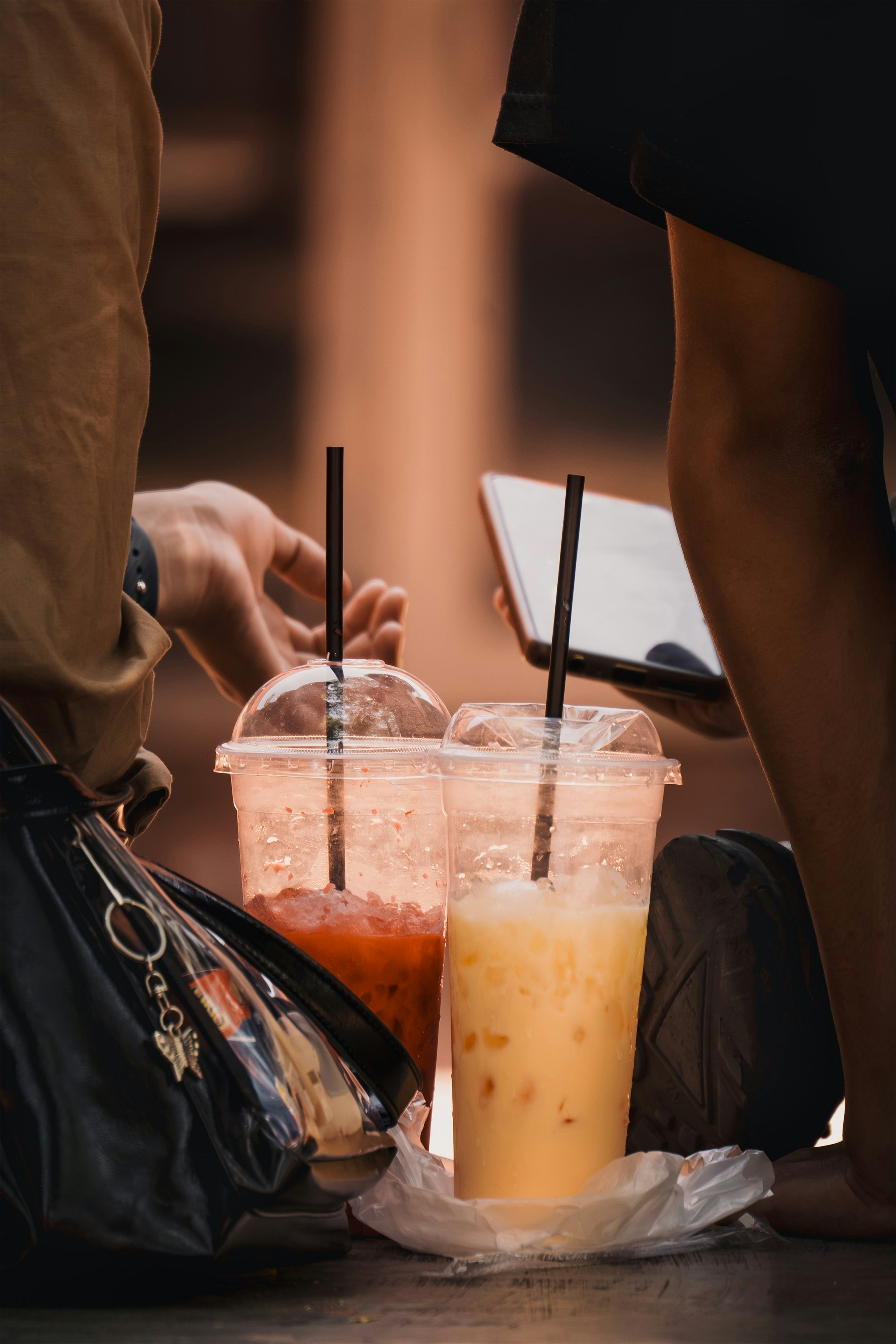 Dos bebidas heladas con pajitas están en el suelo.