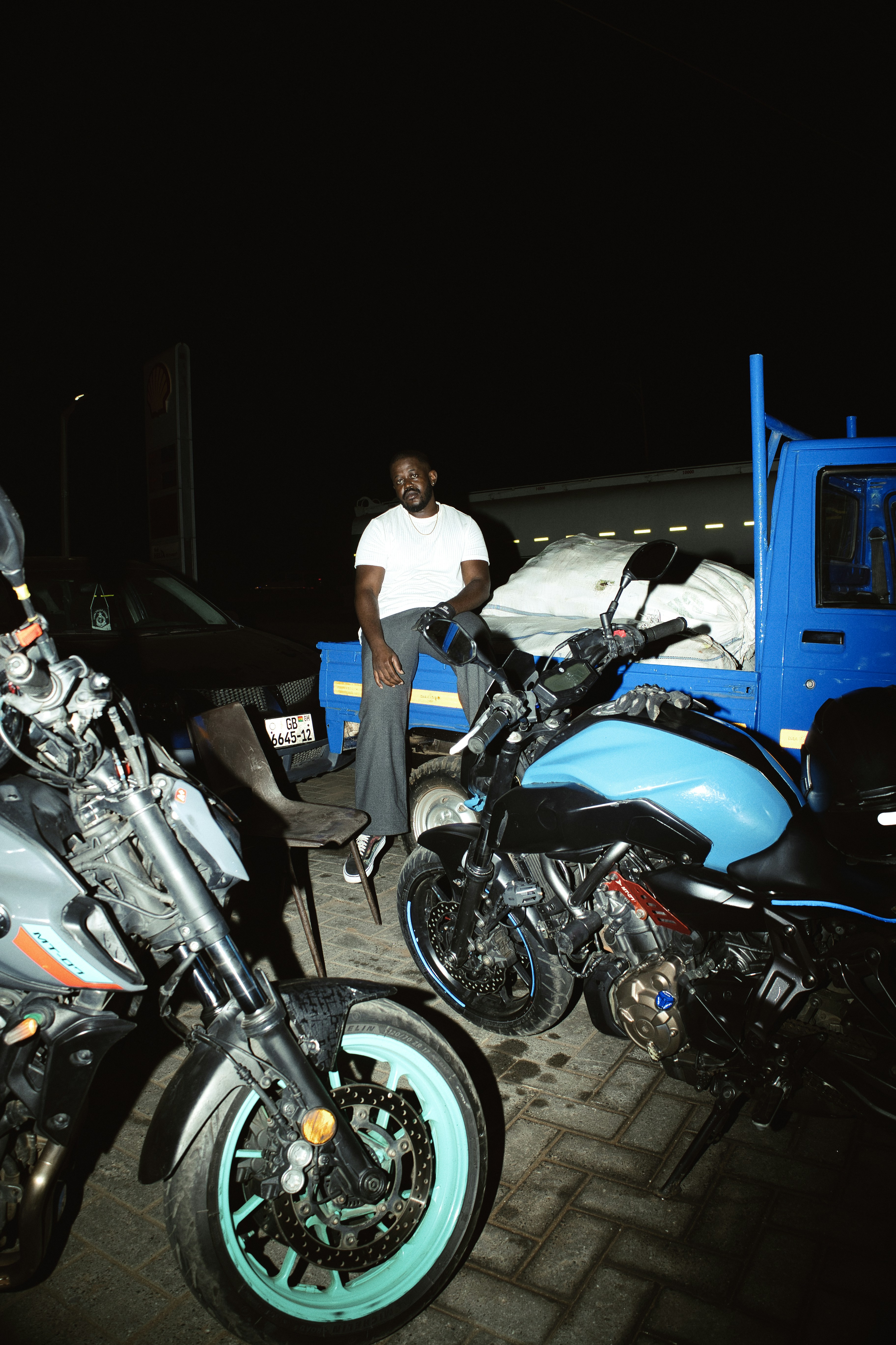 Man sitting on a stool between motorcycles at night
