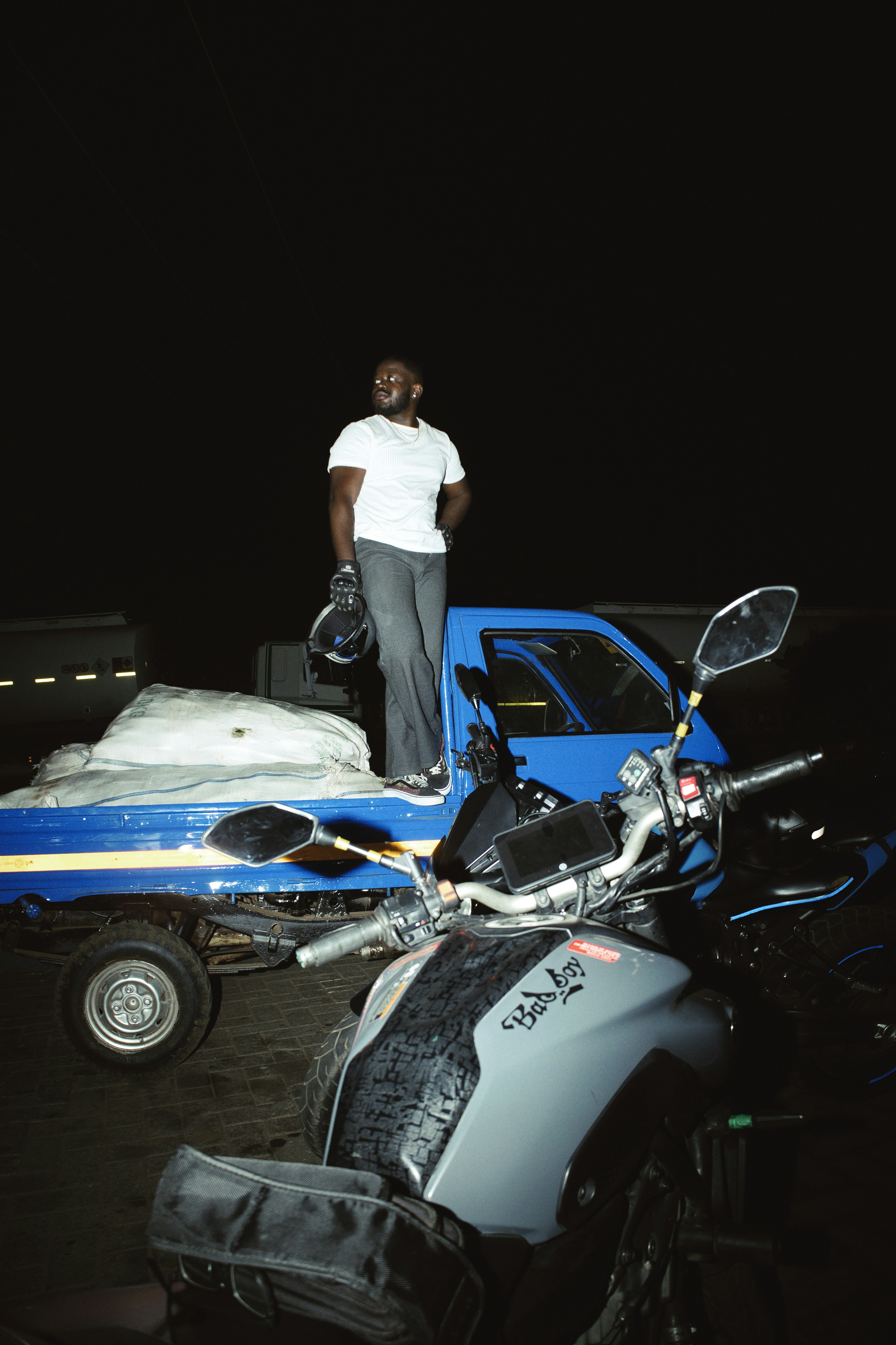 Man standing on truck bed with motorcycles nearby