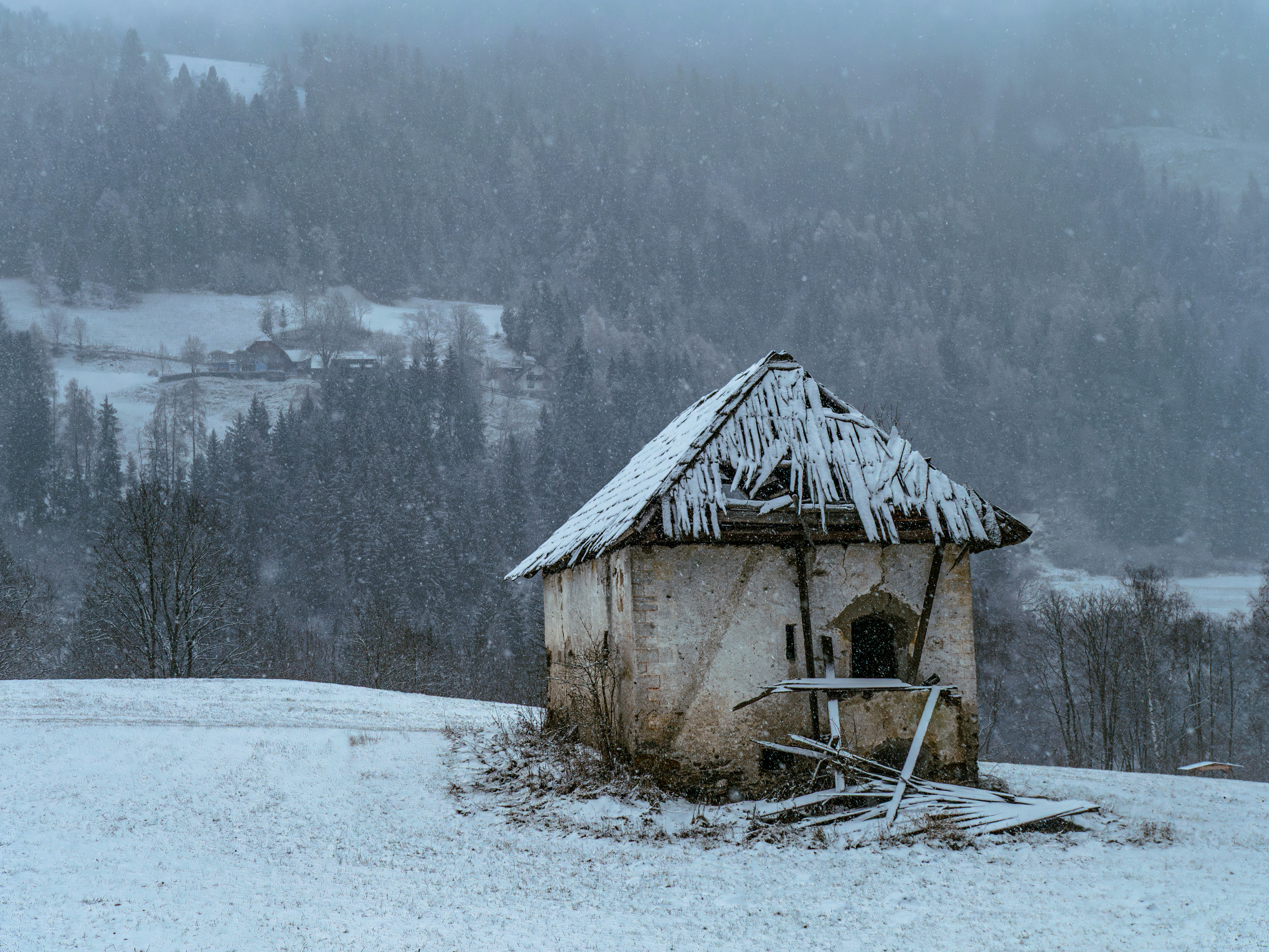 Small abandoned building in a snowy landscape.