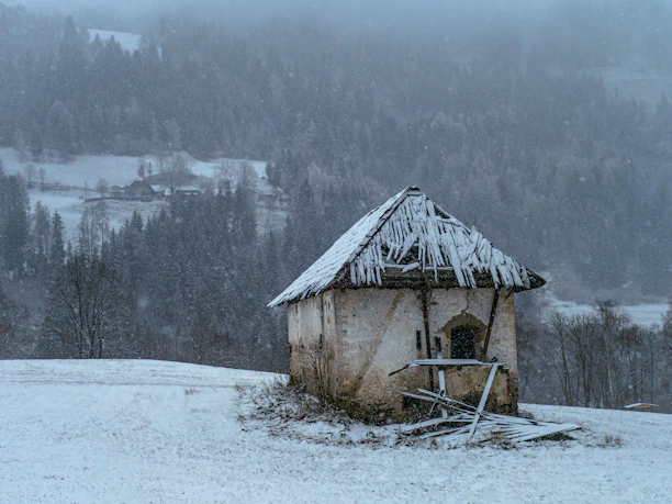 Small abandoned building in a snowy landscape.
