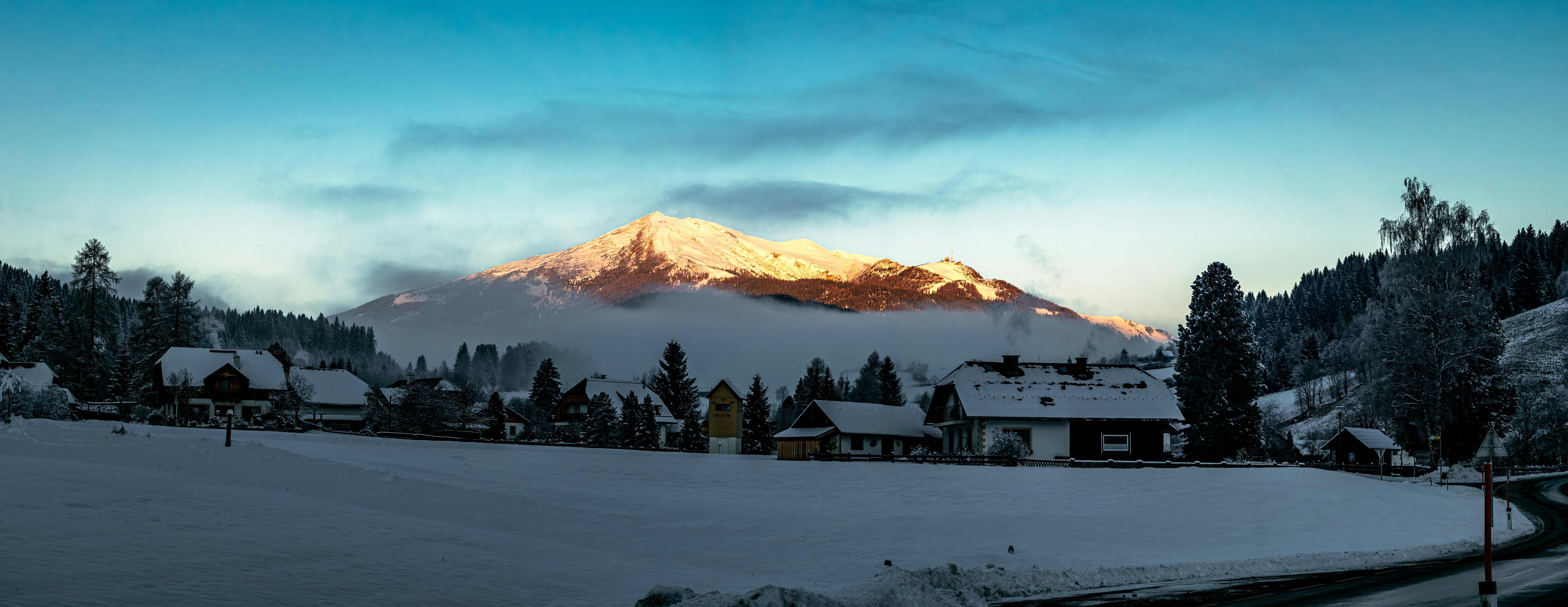 Snowy village with mountain illuminated by sunset.