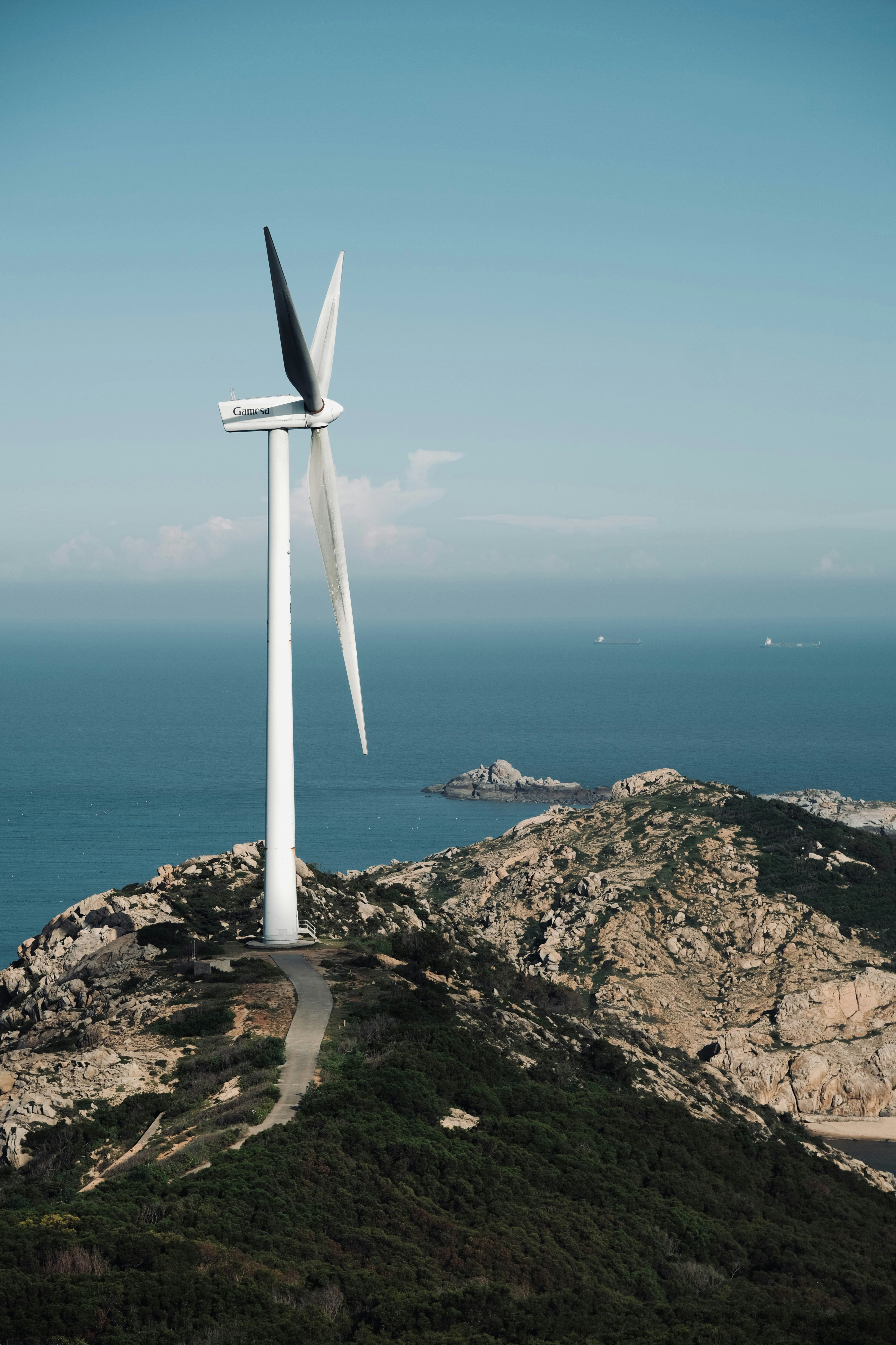 Wind turbine on a rocky coastal hill overlooking the ocean